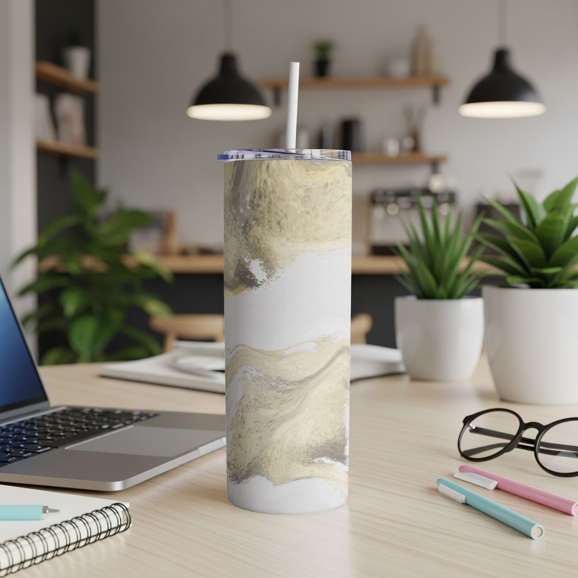 White and gold marbled tumbler with straw on a desk.