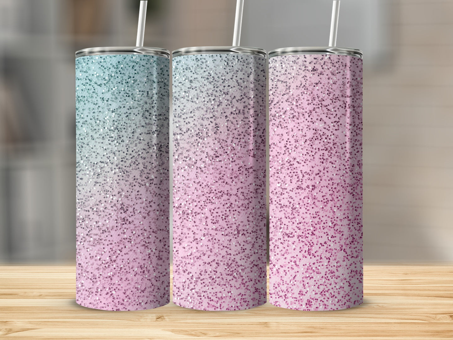 Three glitter tumblers in a gradient of blue to pink with straws.