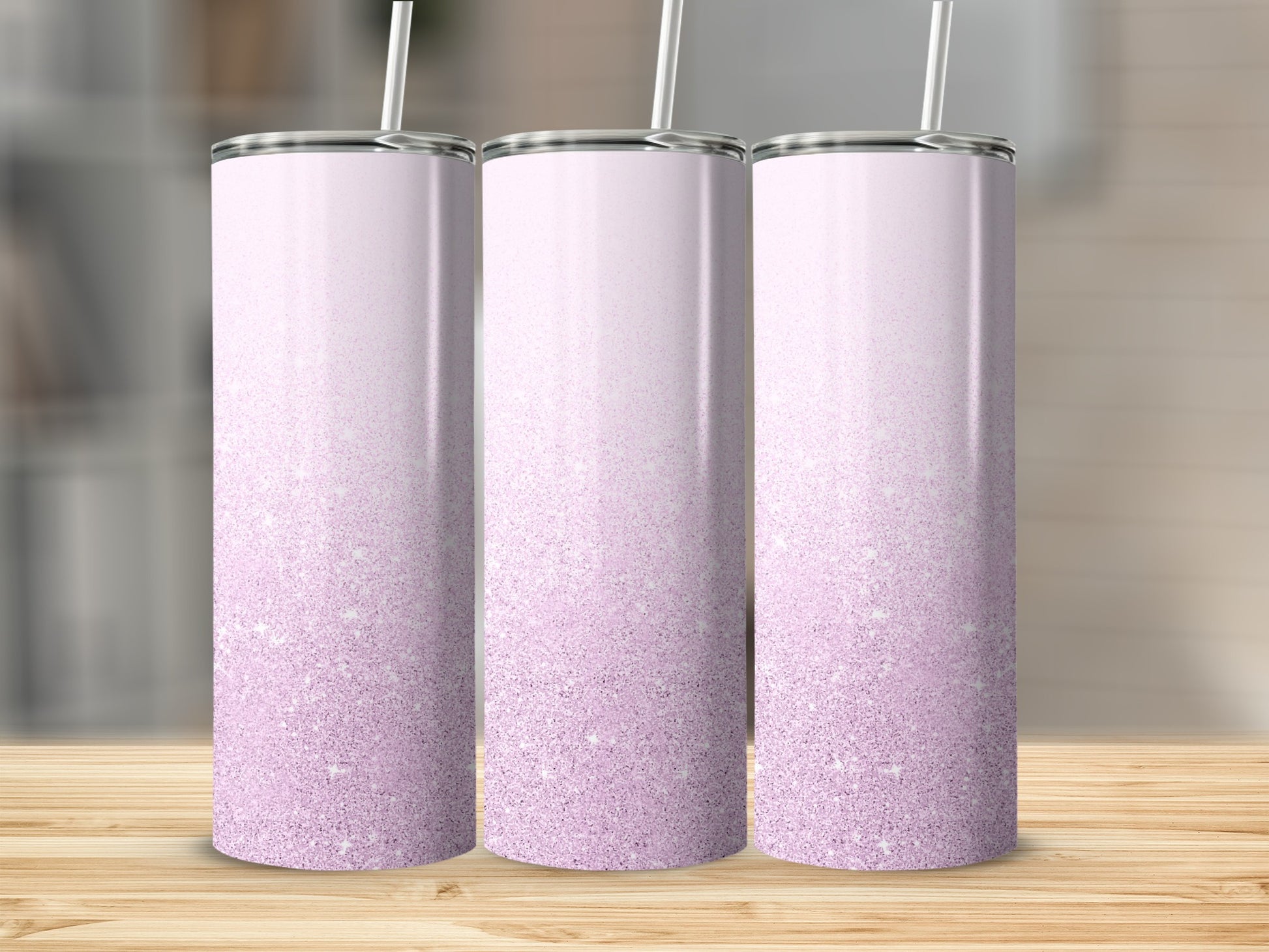 Three tall, skinny tumblers with a pink glitter ombre design and straw.