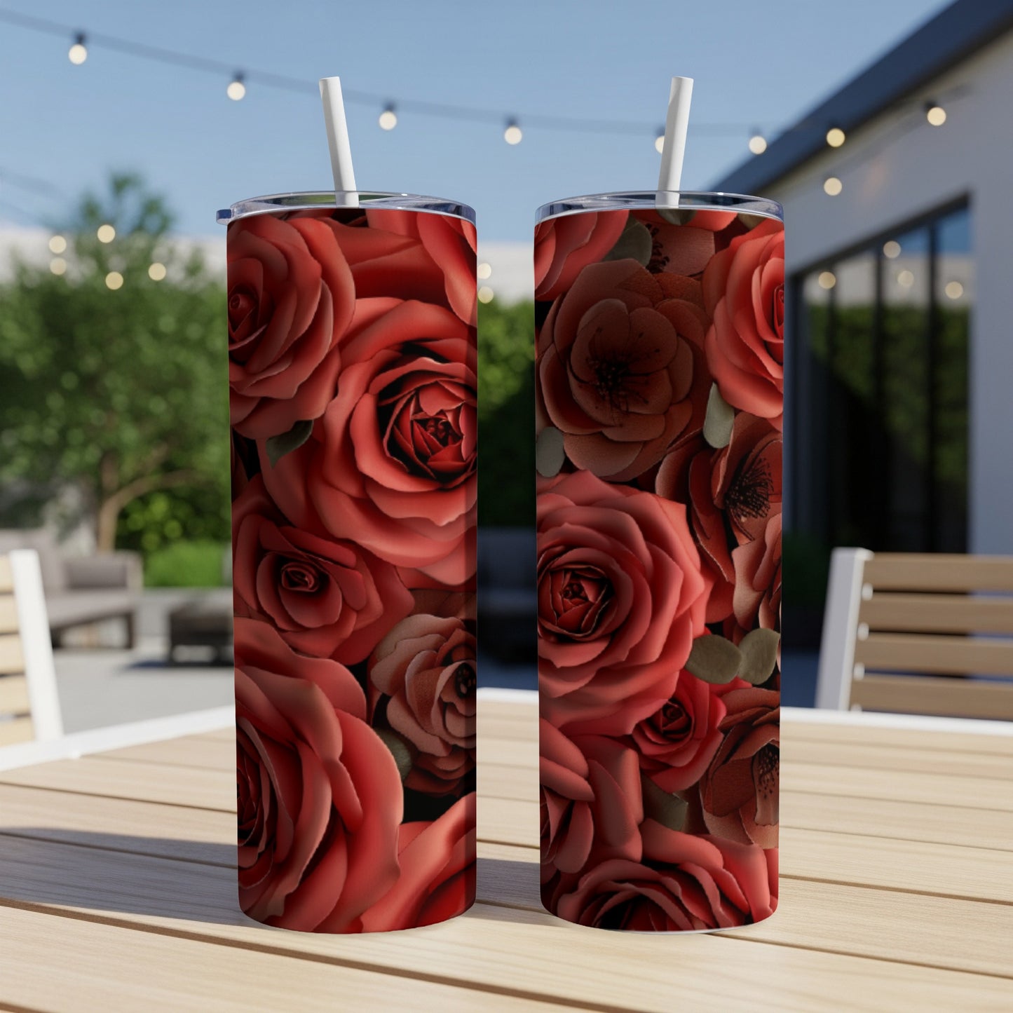 Two red rose tumblers with straws on a wooden table.