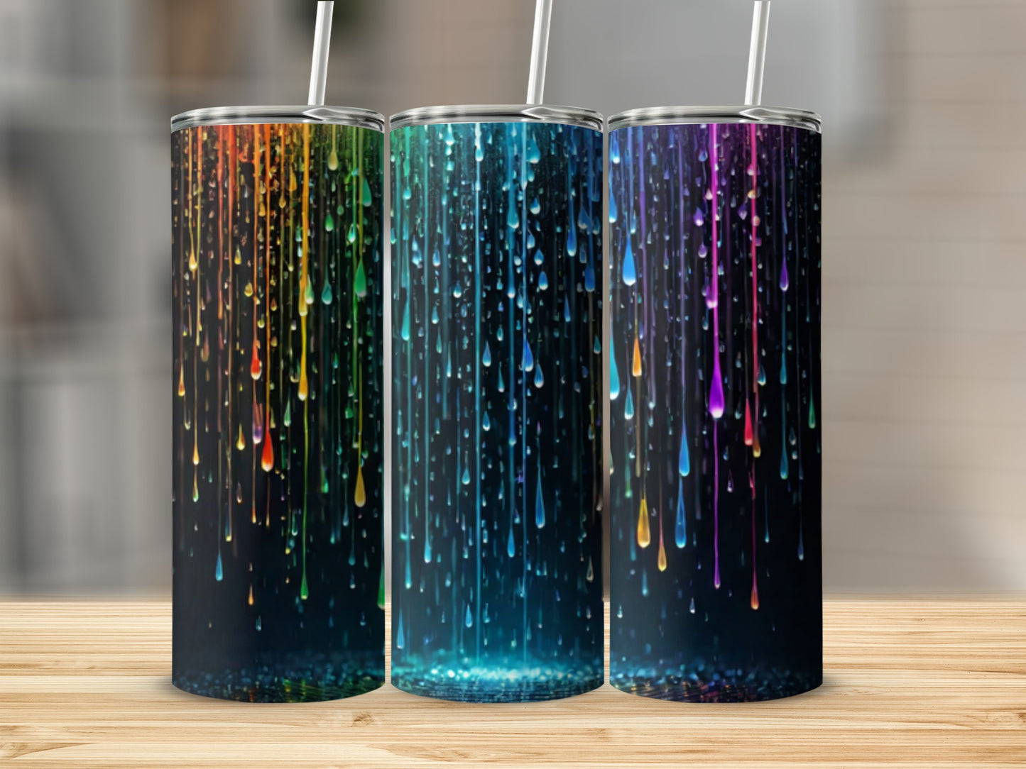 Three tumblers with dripping rainbow paint design on a wooden surface.