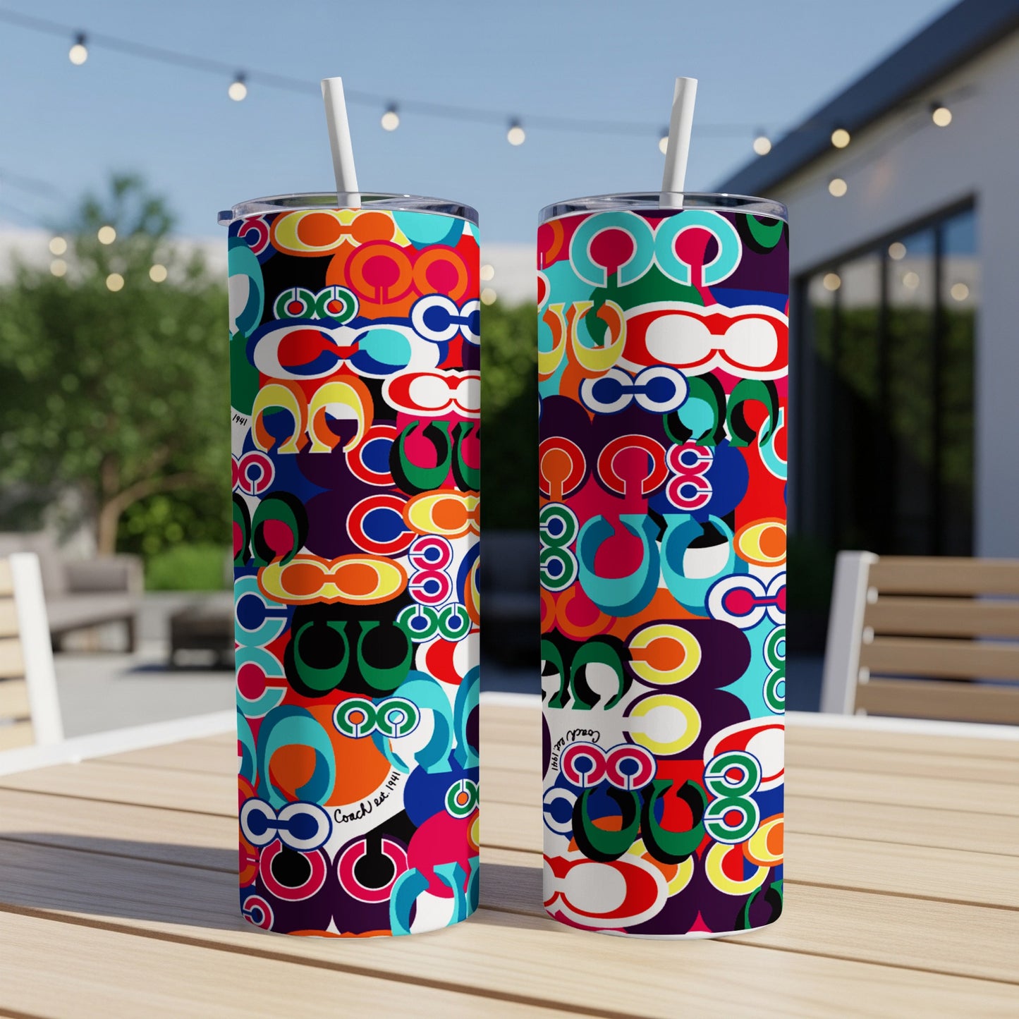 Two tumblers with colorful interlocking C logo pattern on a wooden table.