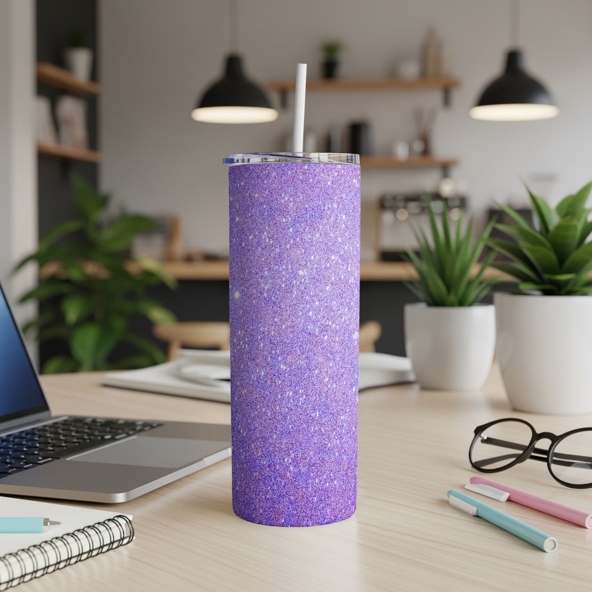 Purple glitter tumbler with a white straw on a desk with a laptop.