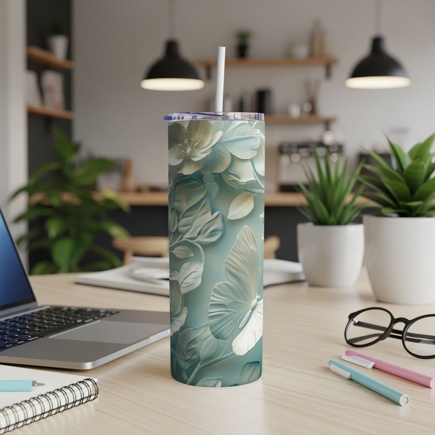 White butterfly and floral pattern on a blue-green insulated tumbler with straw.