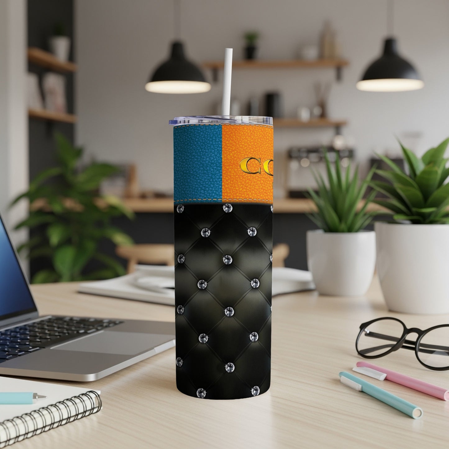 Tumbler with orange, blue, and diamond-tufted black design sits on a desk.