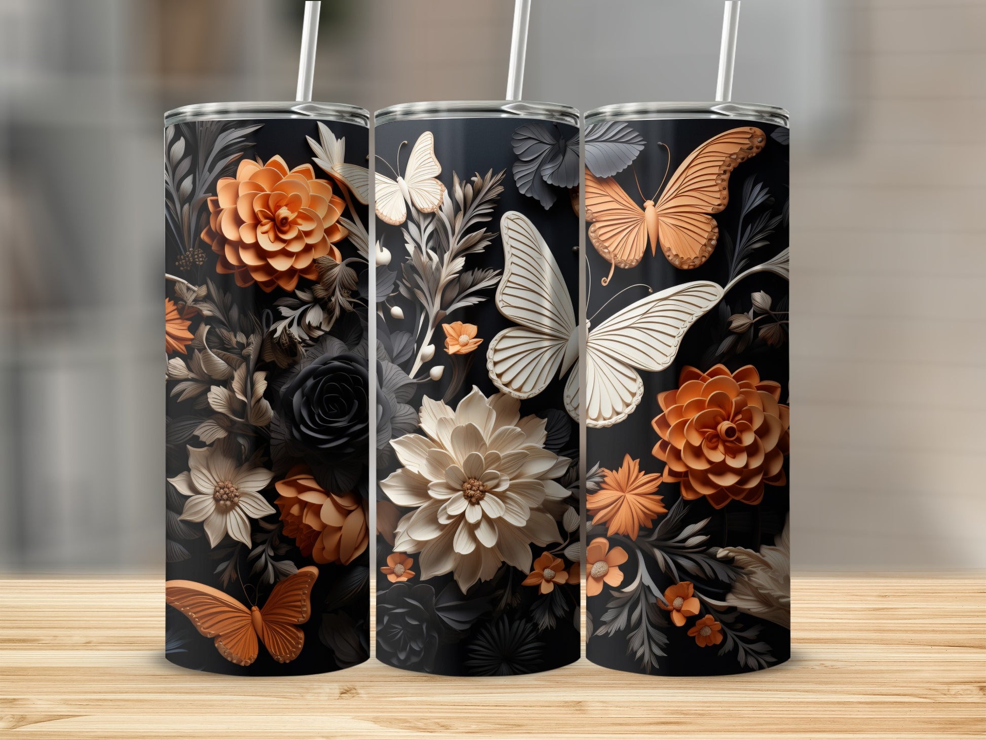 Three tumblers with floral and butterfly designs on a wooden surface.