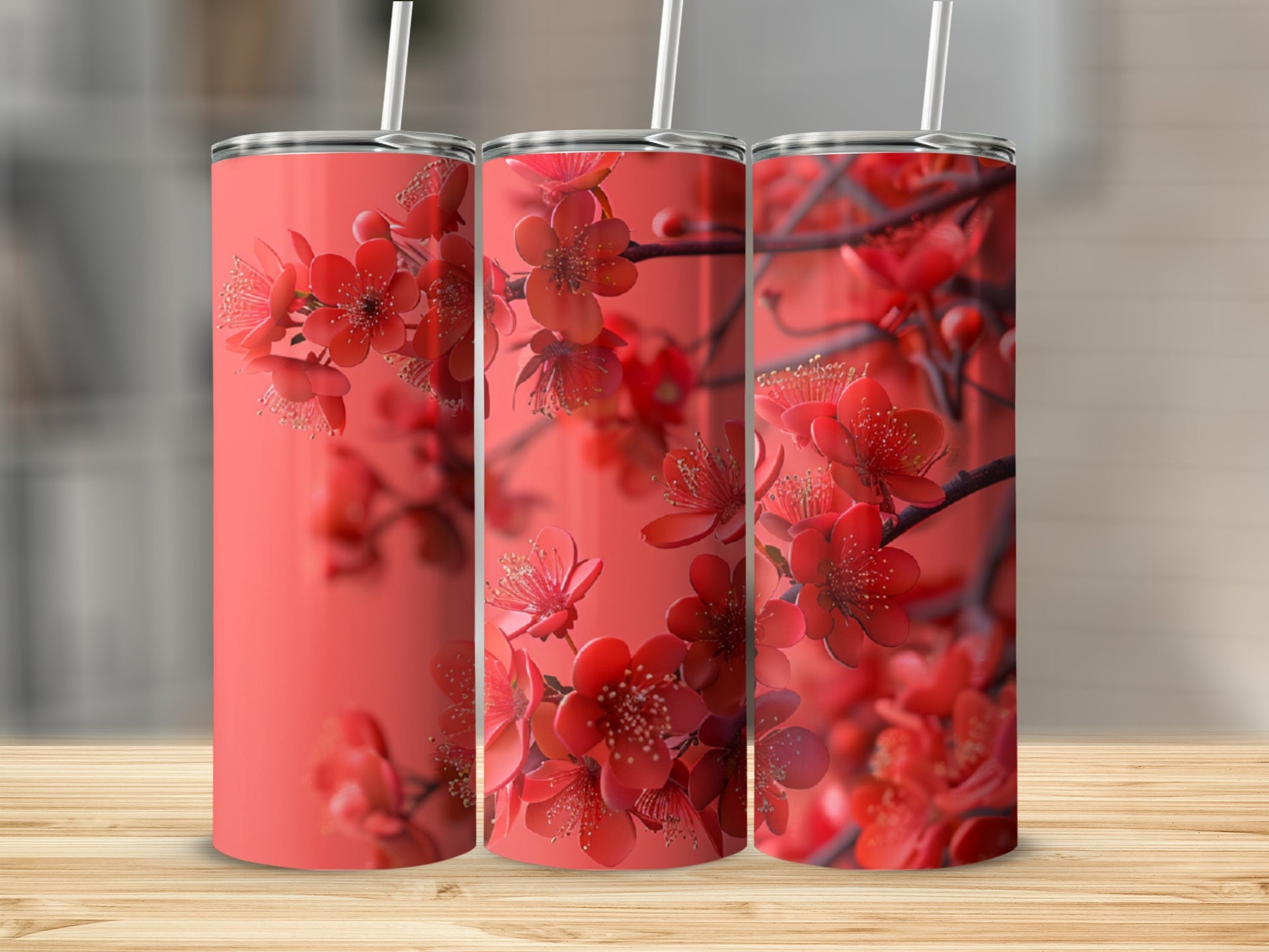 Three coral tumblers with blooming red cherry blossoms against a blurred background.