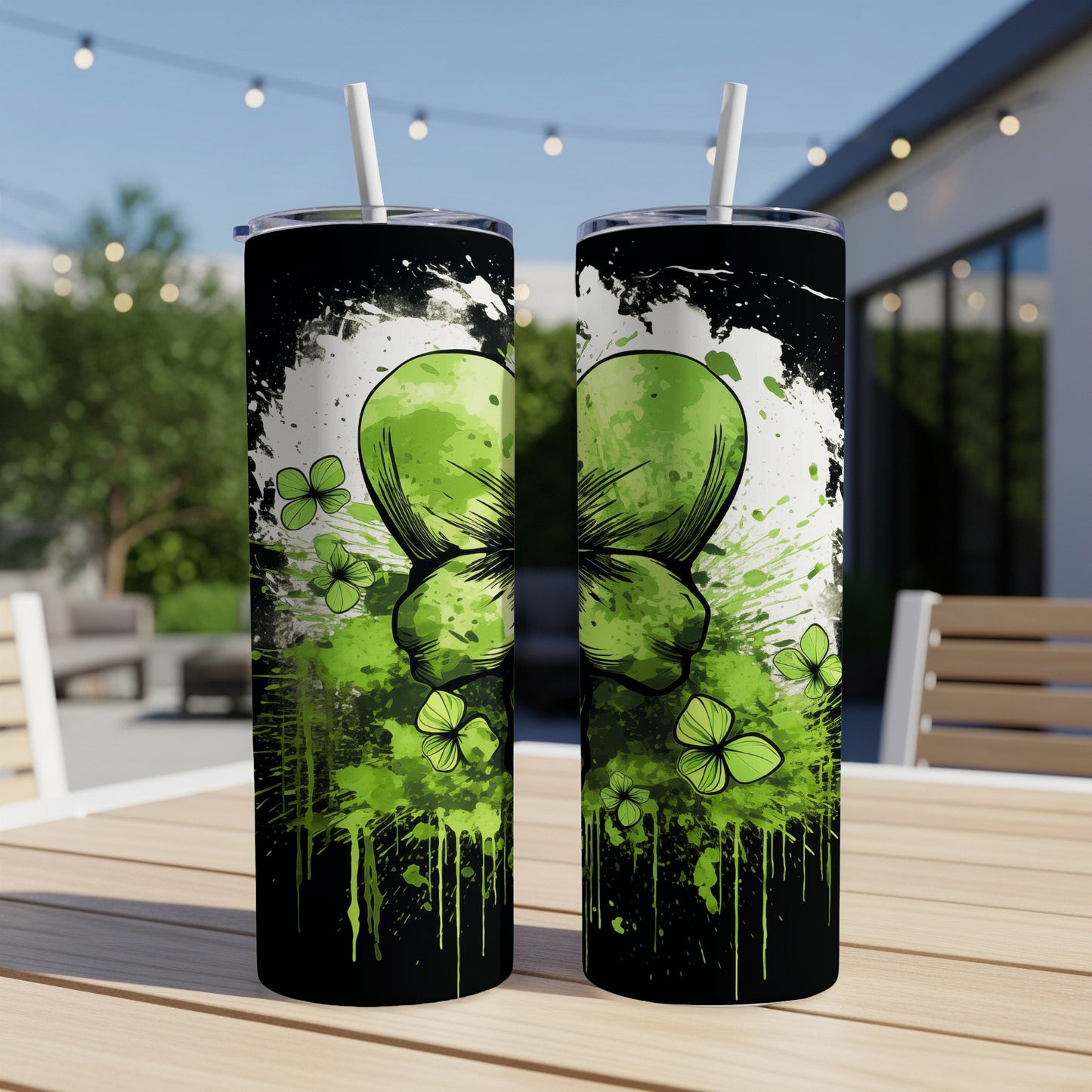 Two tumblers with a green shamrock design on an outdoor table.