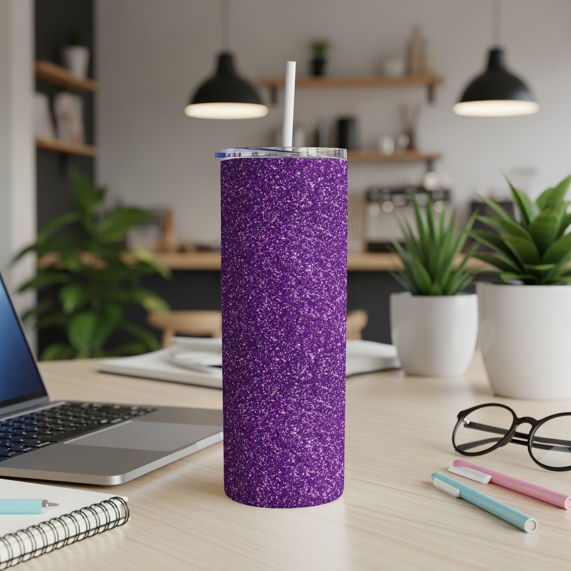 Purple glitter tumbler with straw on a desk next to a laptop and glasses.