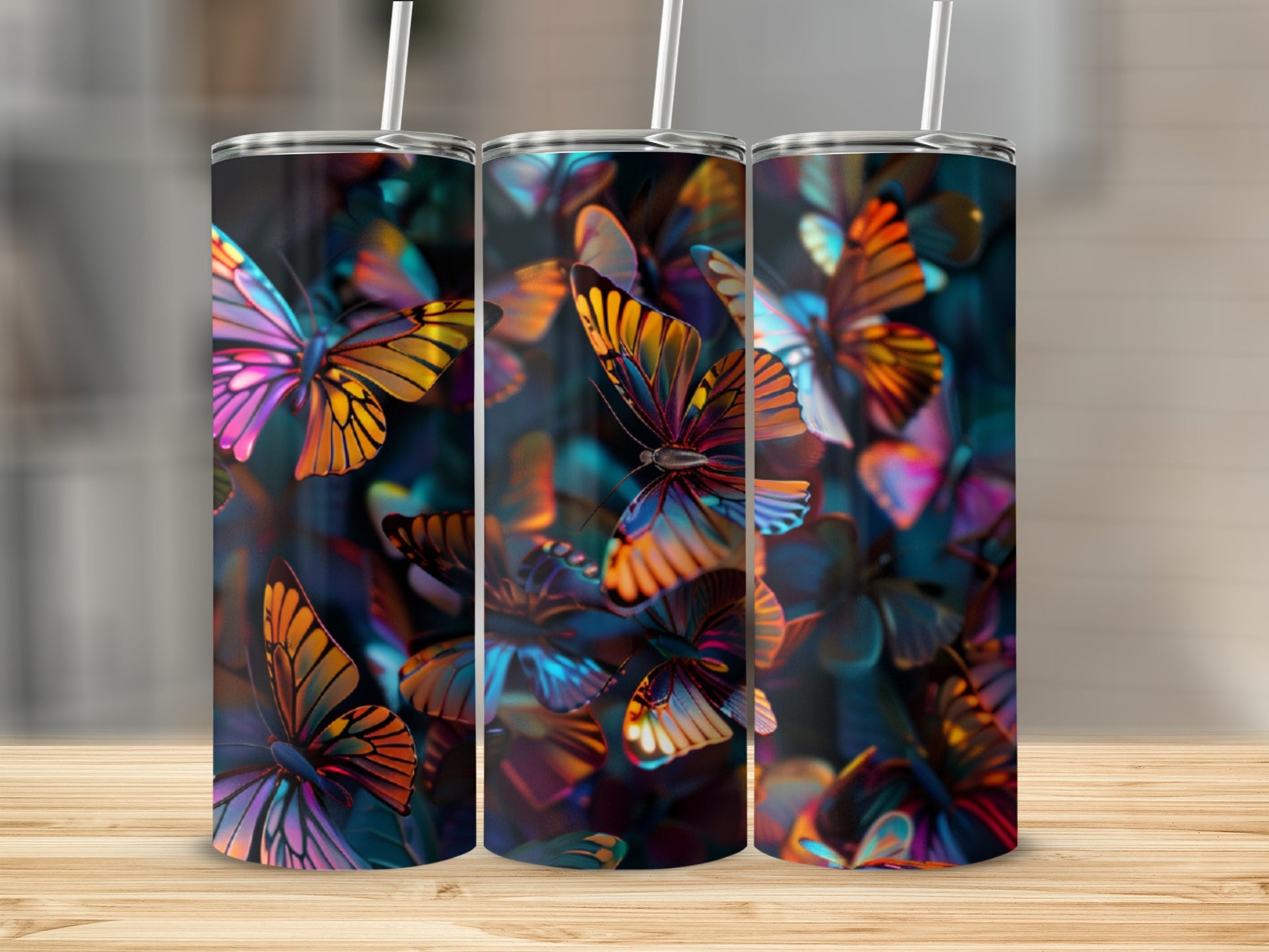 Three colorful butterfly tumblers with straws on a wooden surface.