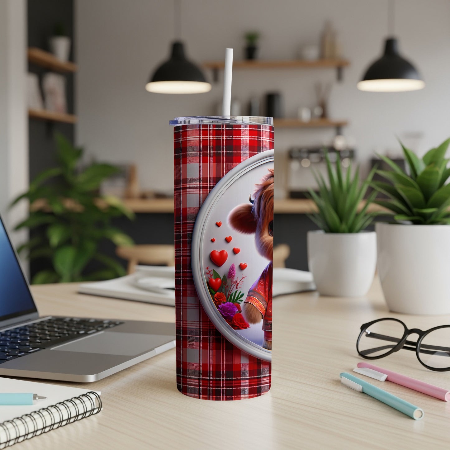 Red plaid tumbler with cartoon cow and hearts, on a desk.
