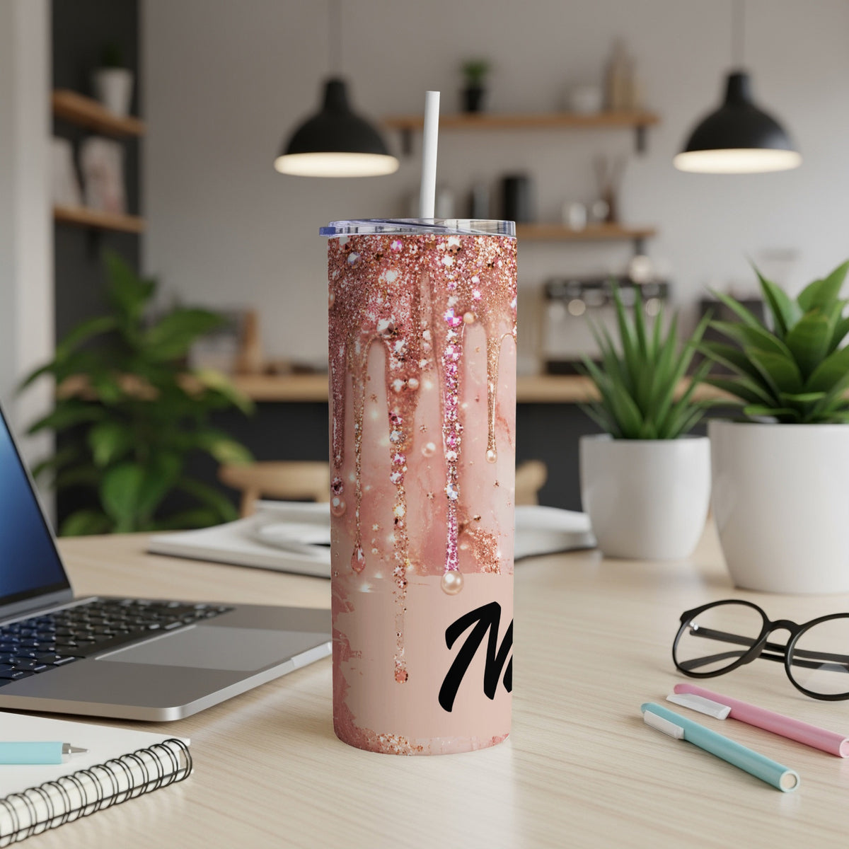 Rose gold glitter drip tumbler with black "Mom" text, on a desk.