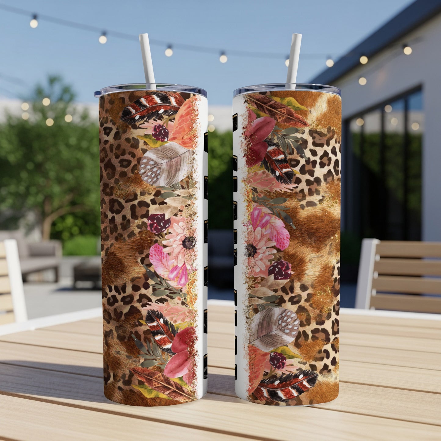 Two tumblers with leopard print, feathers, and floral designs on a wooden table.