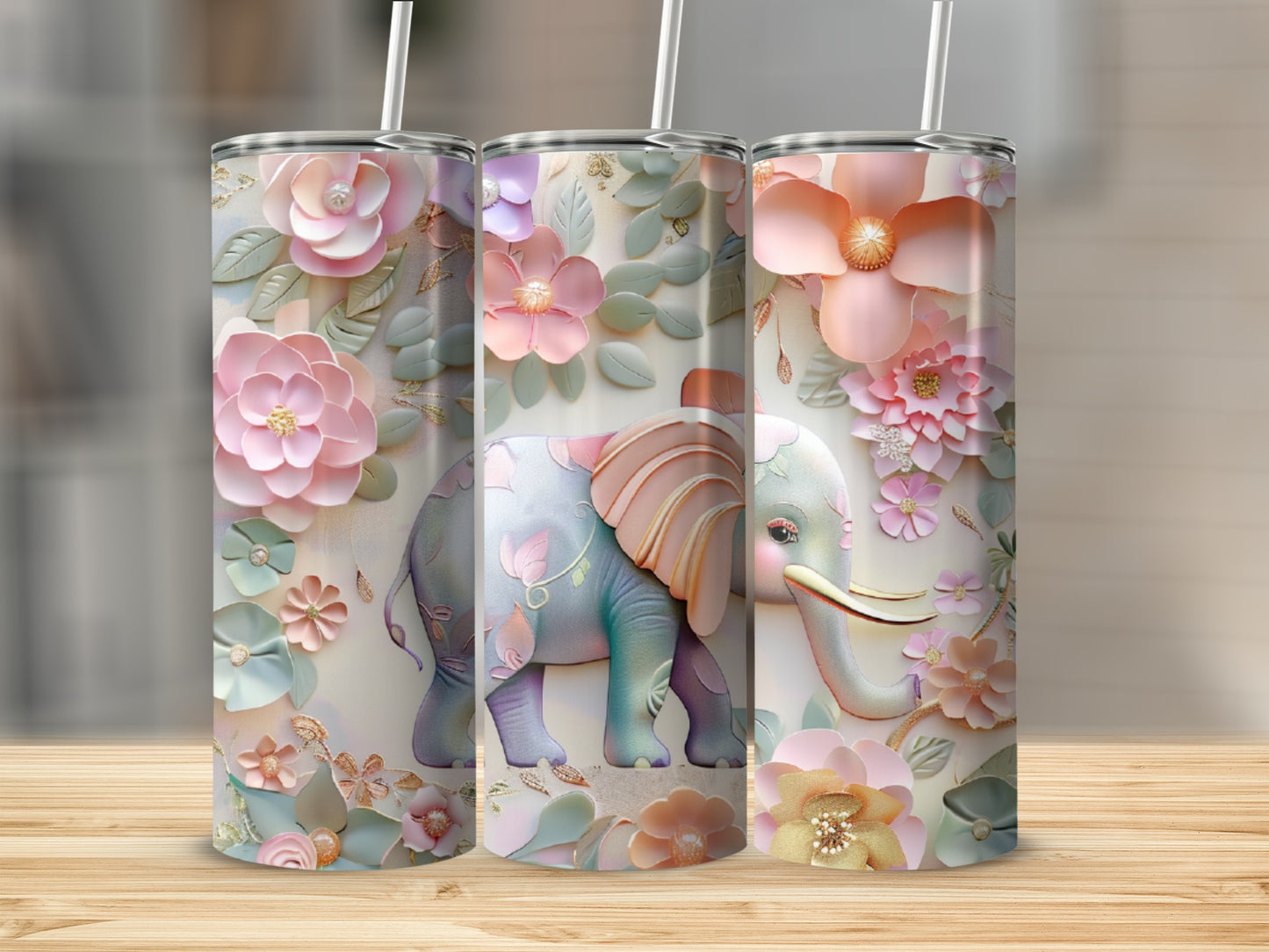Three tumblers with floral elephant designs on a wooden surface.