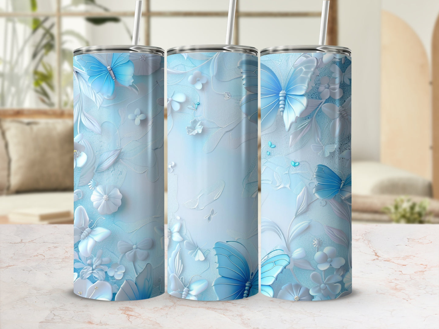 Three blue butterfly and floral patterned tumblers with straws.