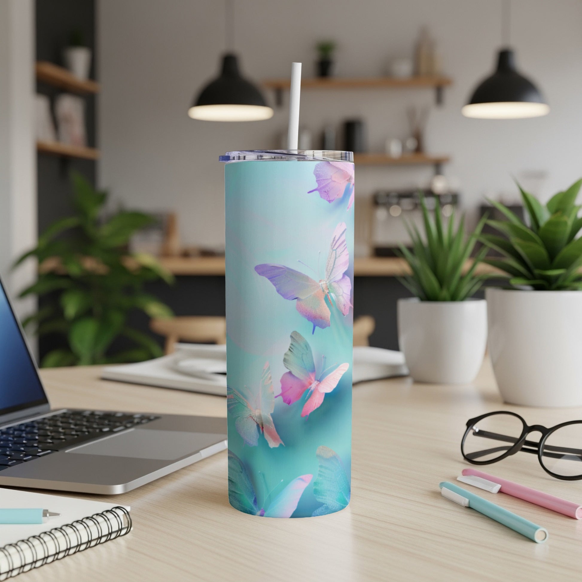 Light blue tumbler with iridescent butterflies, straw in lid, on a desk.