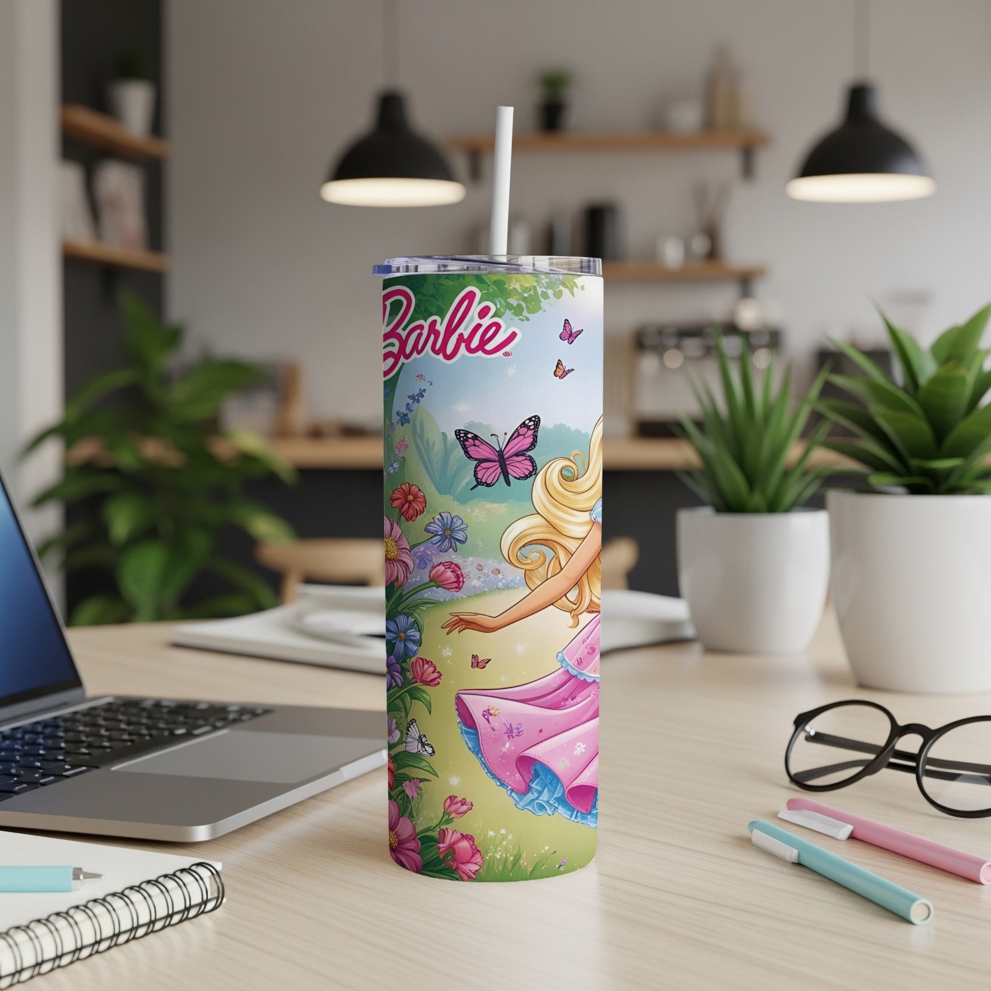 Barbie tumbler with butterflies and flowers on a desk with a laptop.