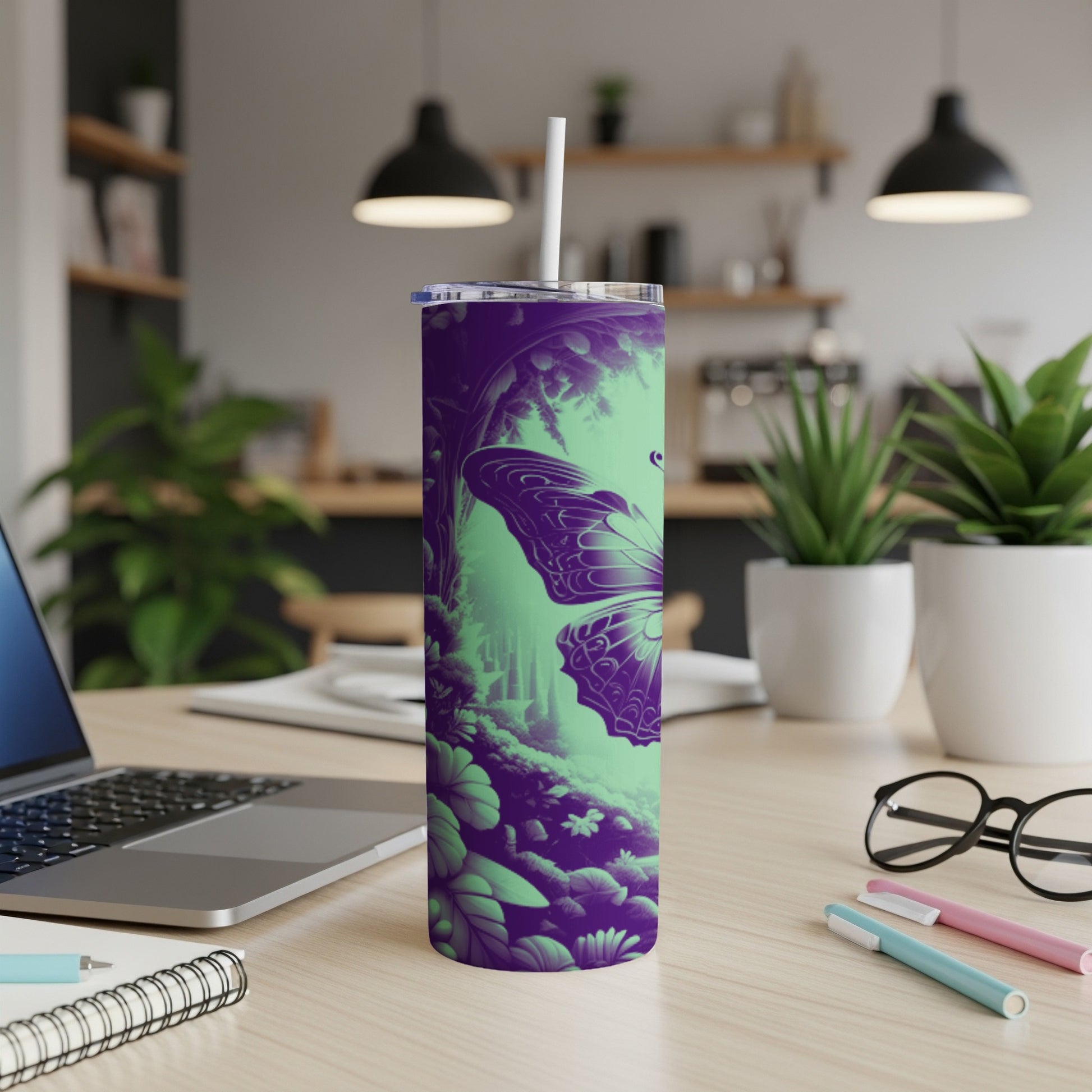 Purple and green butterfly tumbler with straw on a desk.