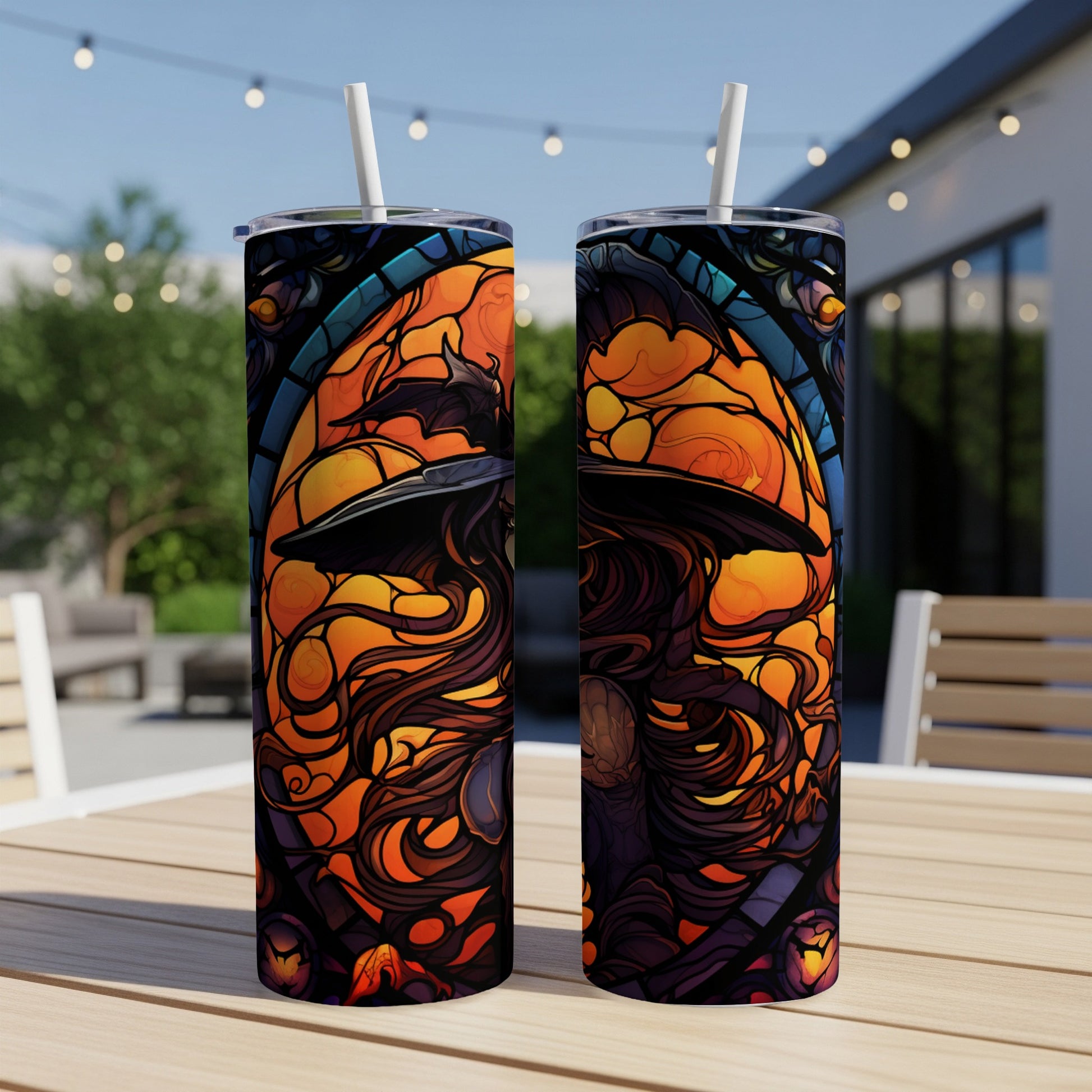 Two tumblers with stained glass witch design on a table outdoors.