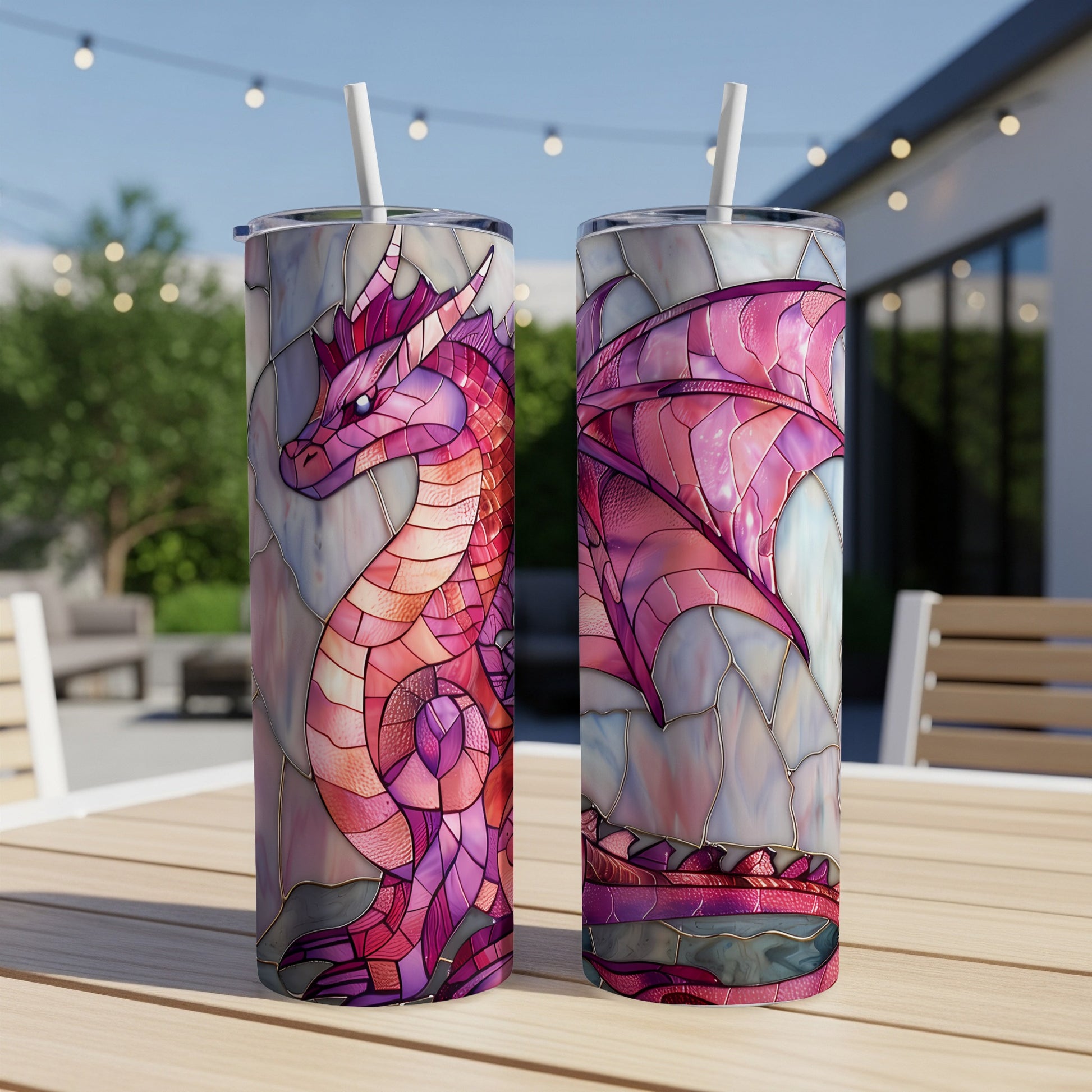 Stained glass dragon design on two tall tumblers with straws, outdoors.