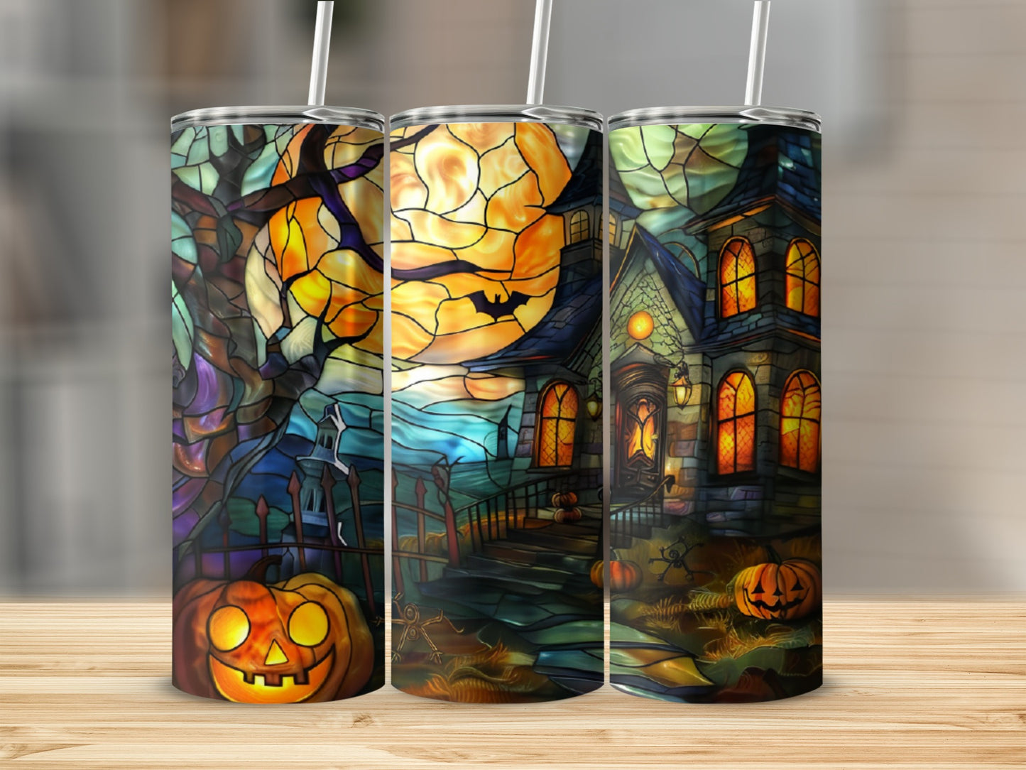 Three Halloween-themed tumblers with stained-glass style designs of pumpkins and haunted houses.