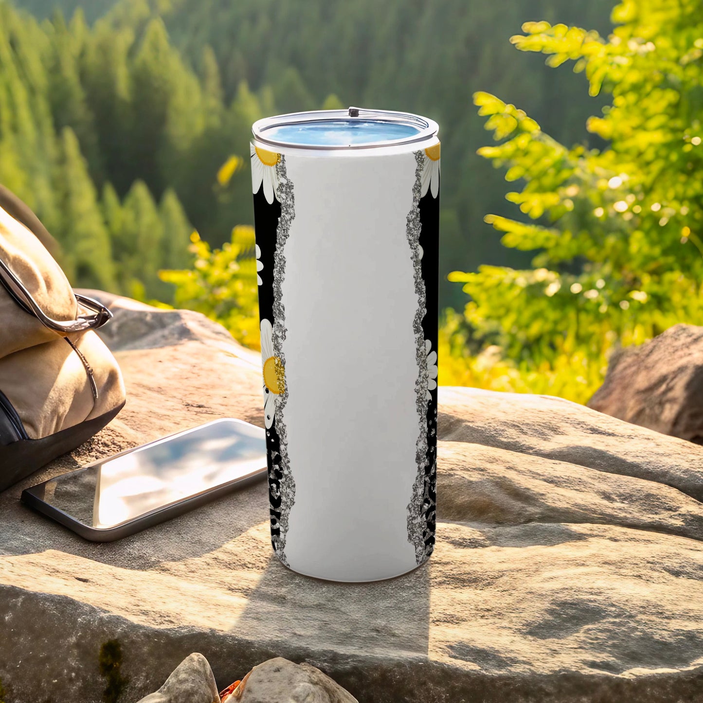 White tumbler with floral border pattern on outdoor rocky surface.