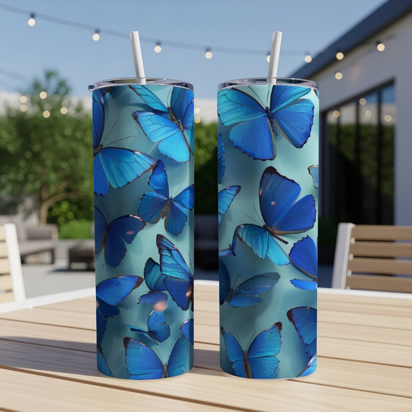Two blue butterfly print tumblers with straws on a wooden table.