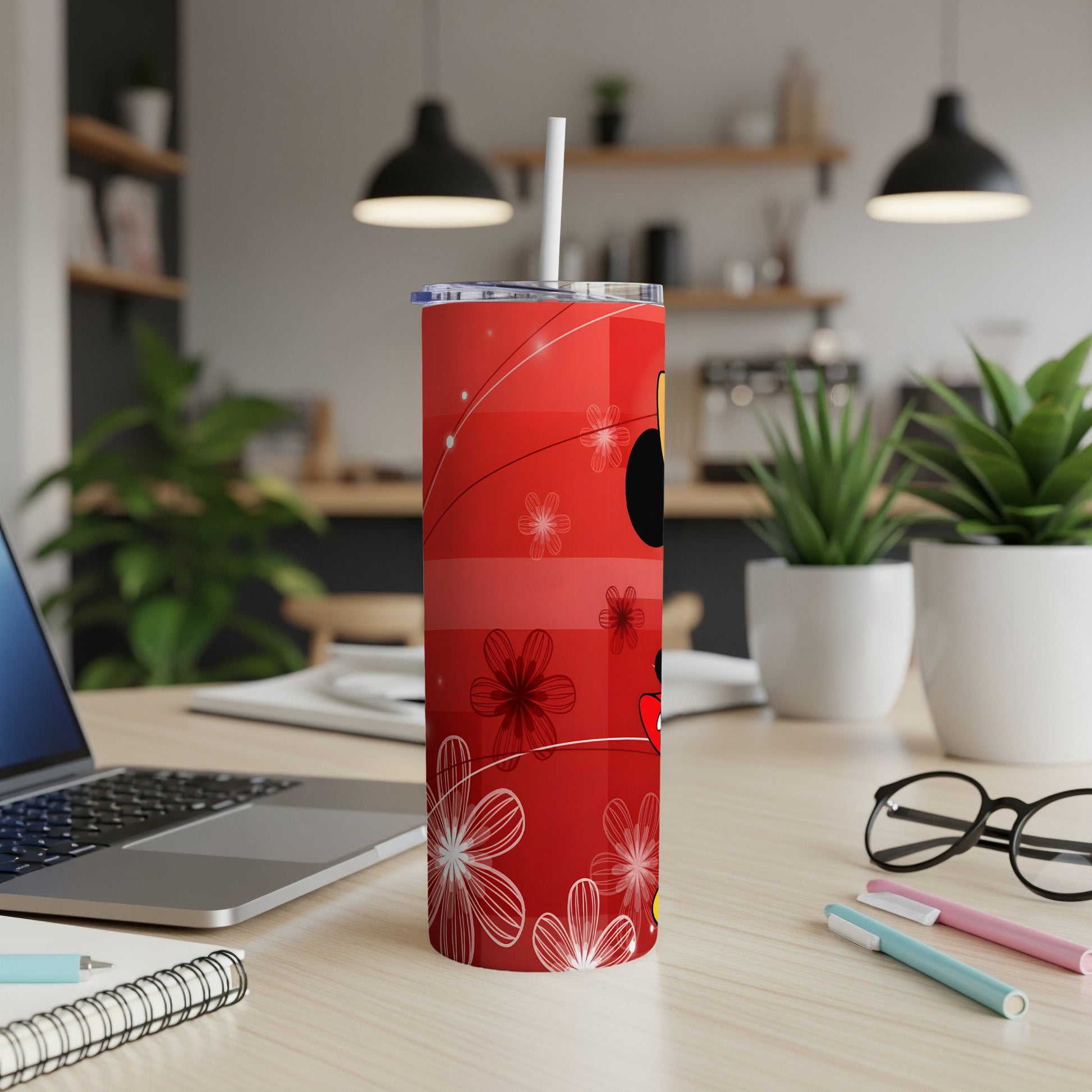 Red tumbler with Mickey Mouse ears and floral pattern on a desk.