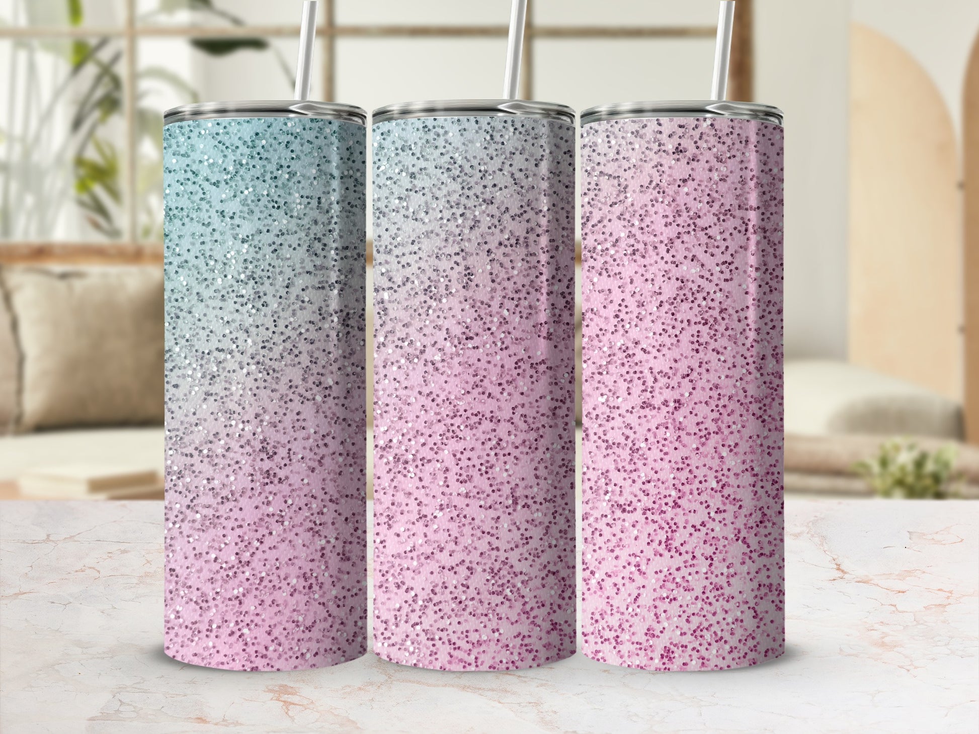 Three glitter tumblers with gradient blue to pink colors on a marble surface.