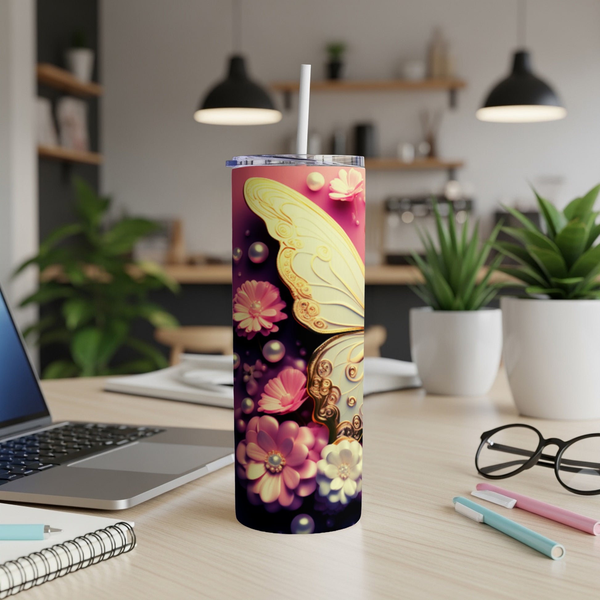 Tumbler with a butterfly and floral design, on a desk.