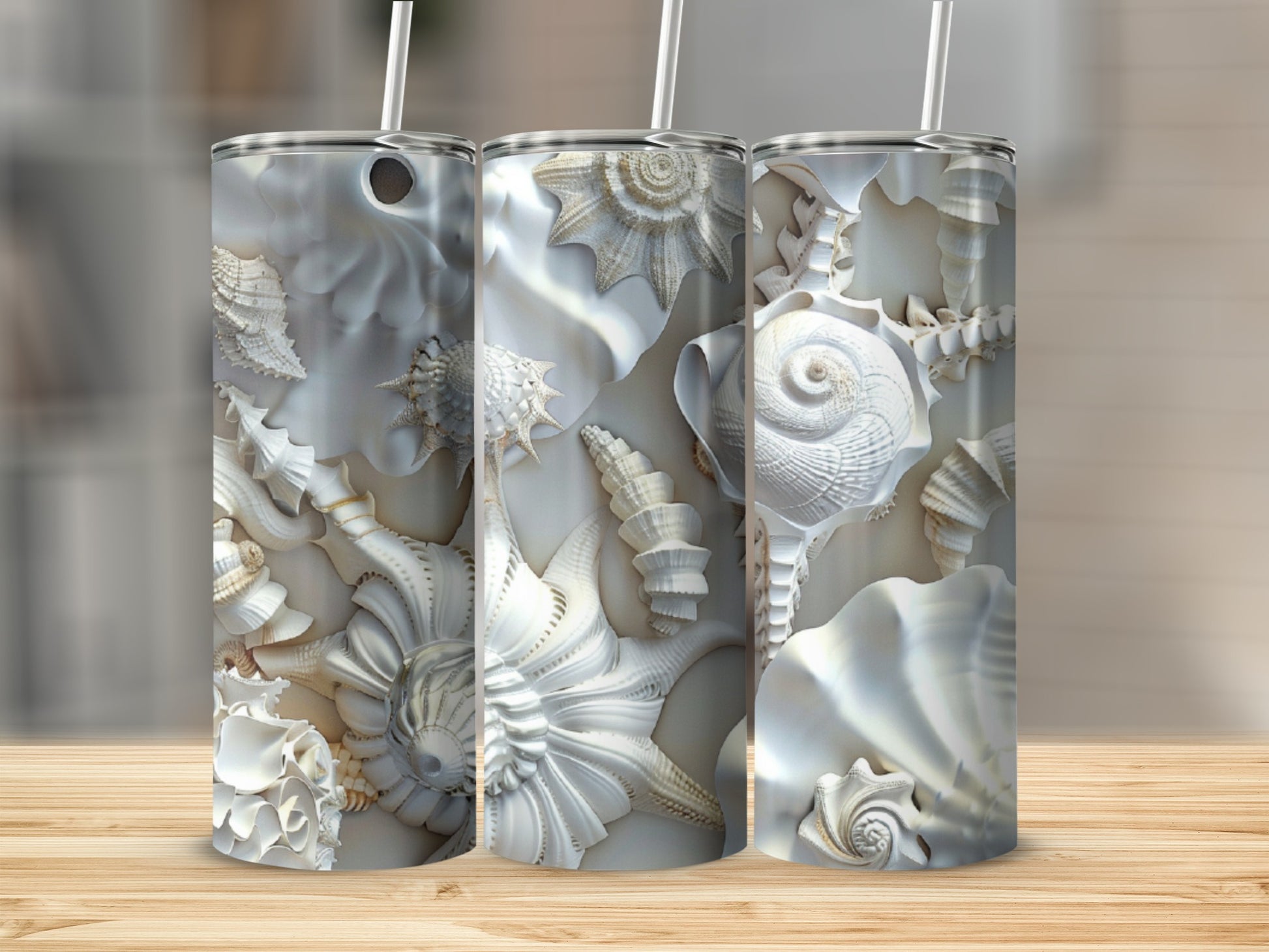 Three tall tumblers with intricate seashell designs and straw lids.
