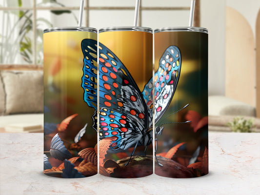 Tumbler with blue and orange butterfly design on blurred autumn leaves background.