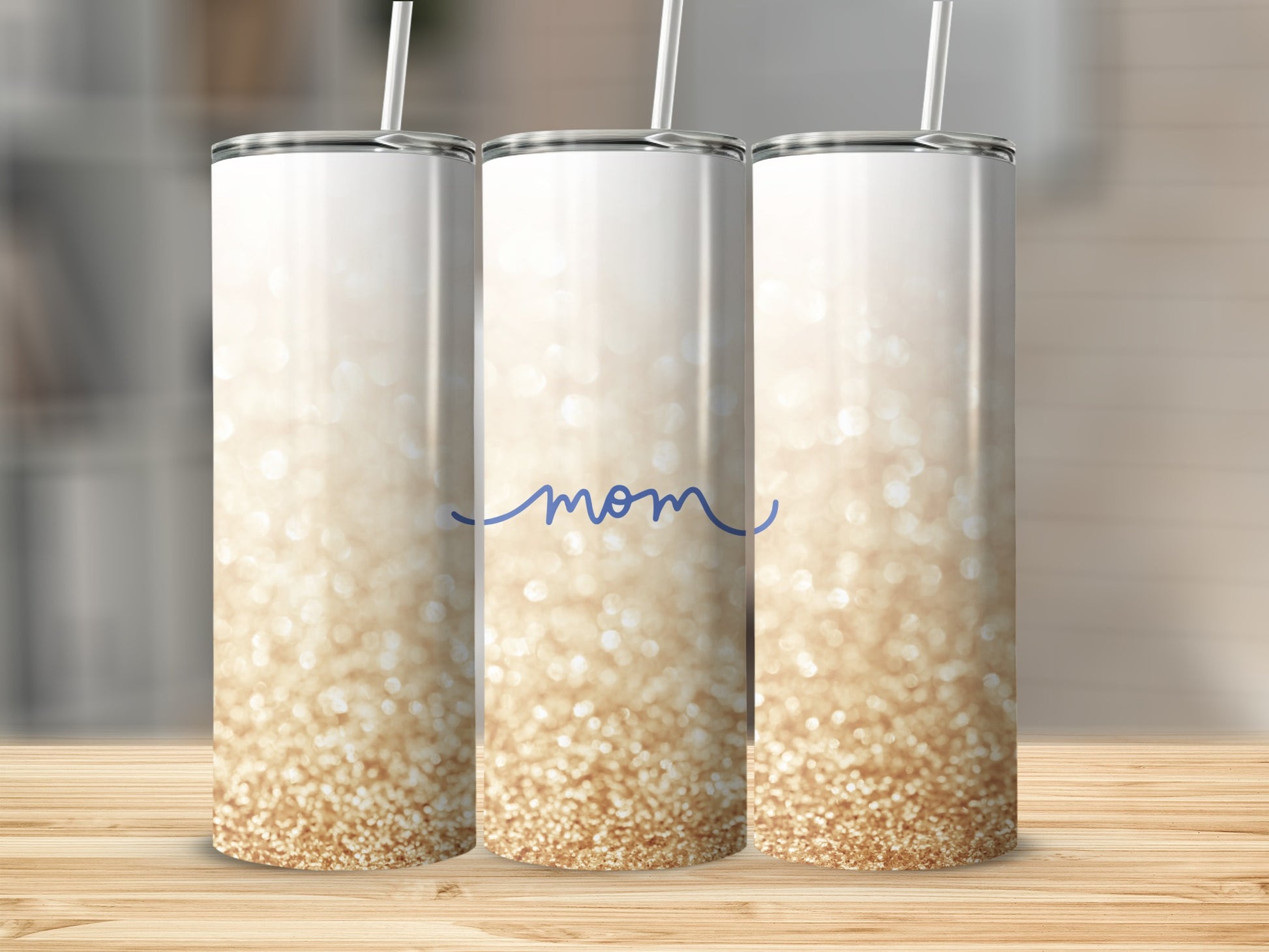White tumbler with "Mom" in blue script and gold glitter ombre.