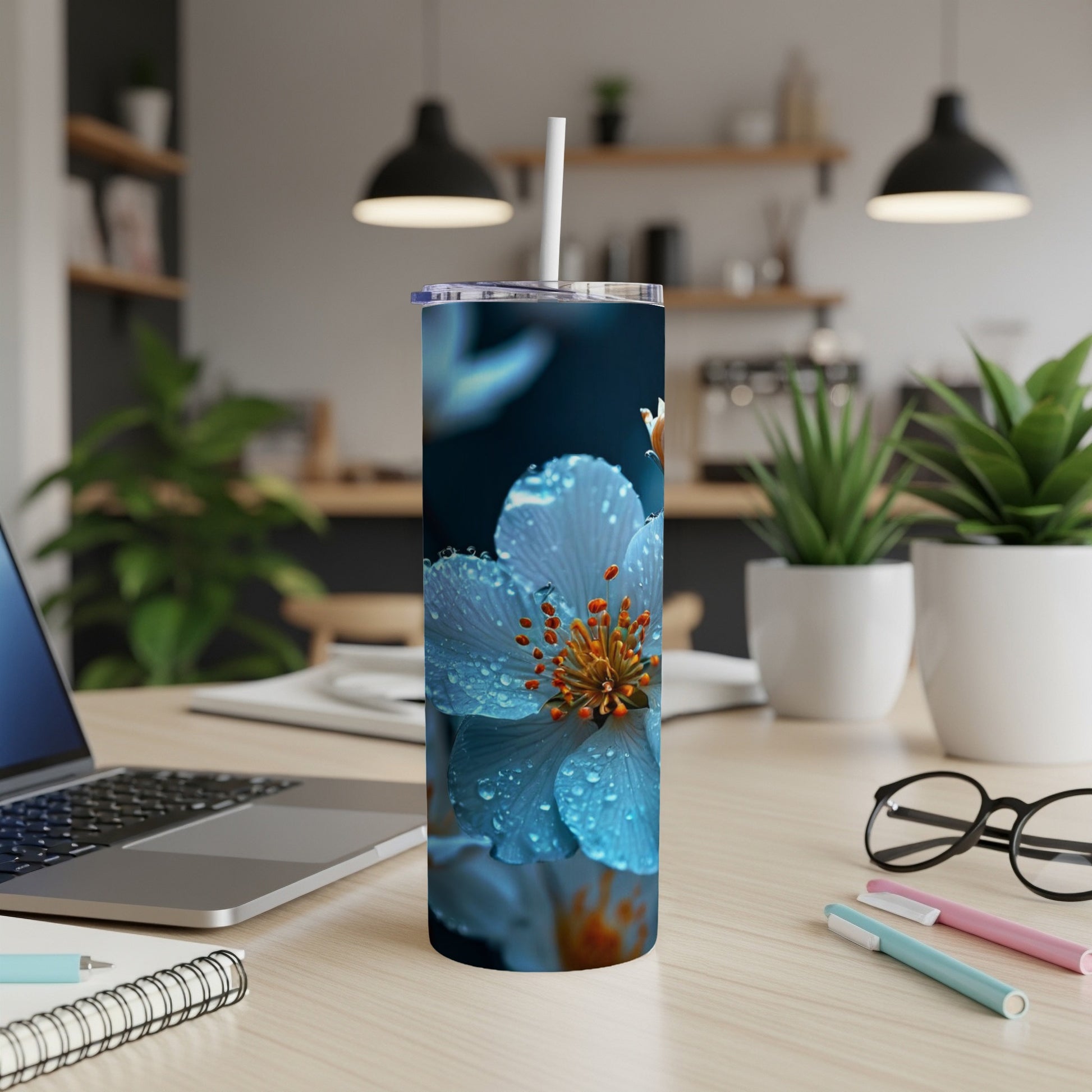 Blue flower with water droplets on a stainless steel tumbler with a straw.