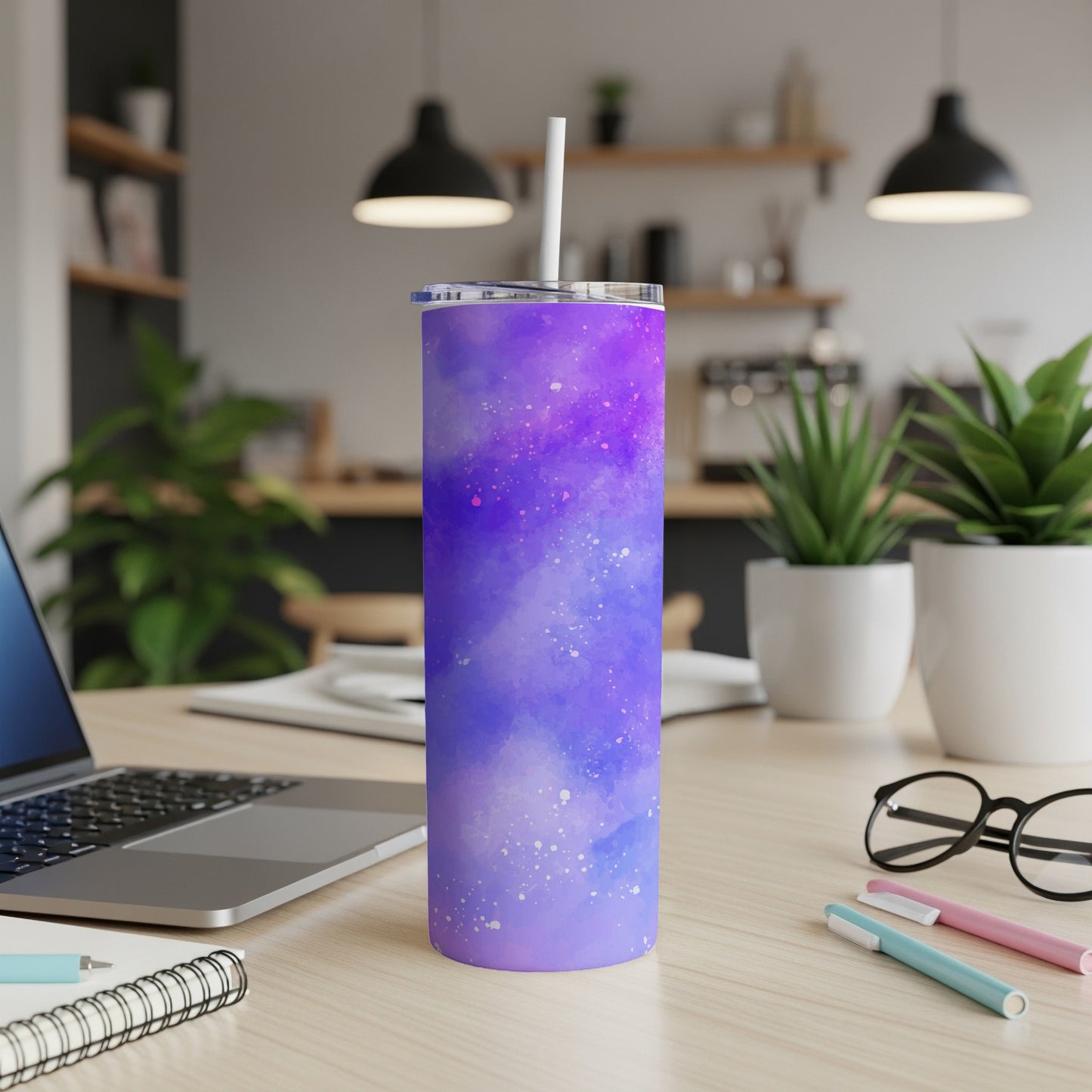 Purple galaxy print tumbler with straw on a desk next to a laptop.