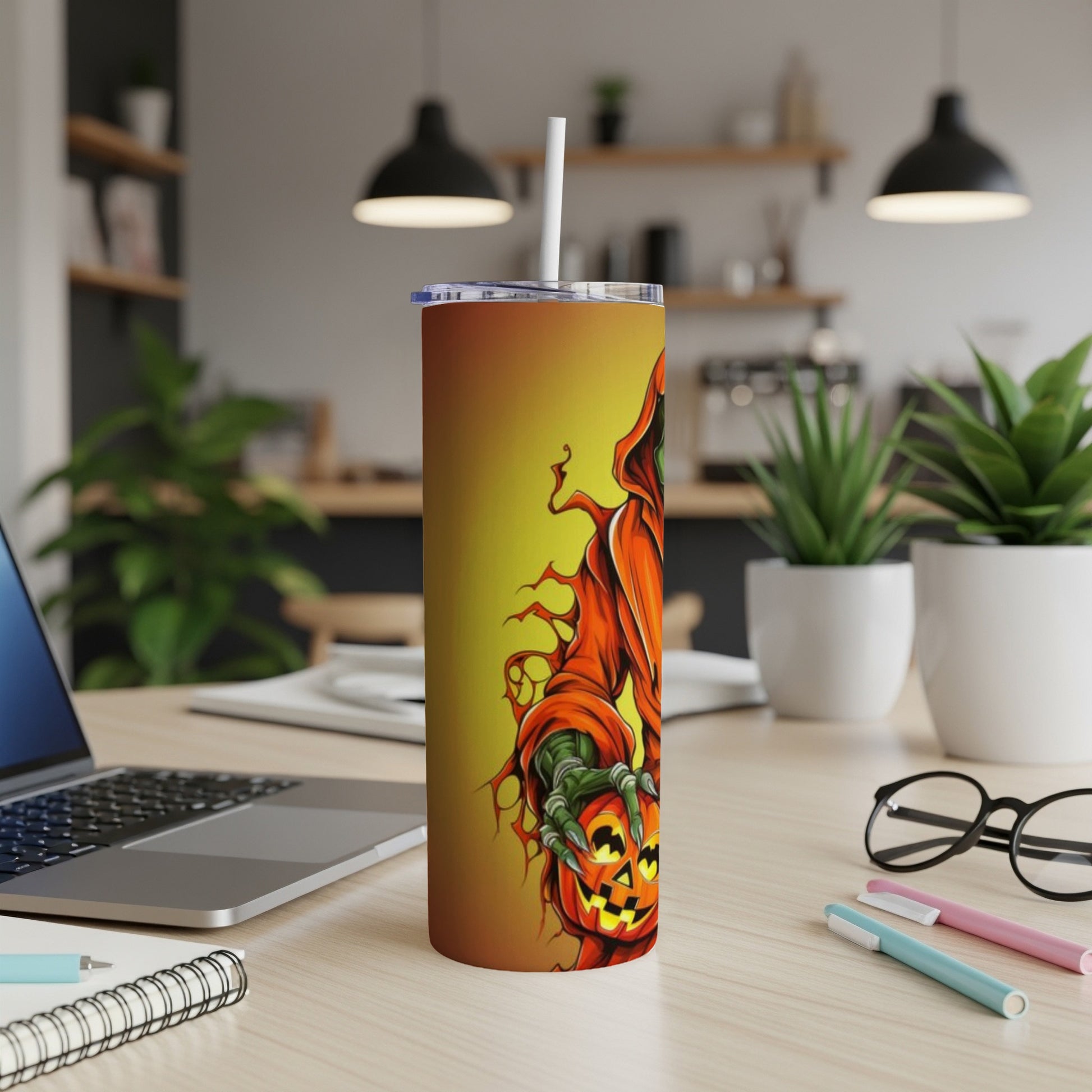 Tumbler with Halloween grim reaper holding a jack-o'-lantern on a desk.