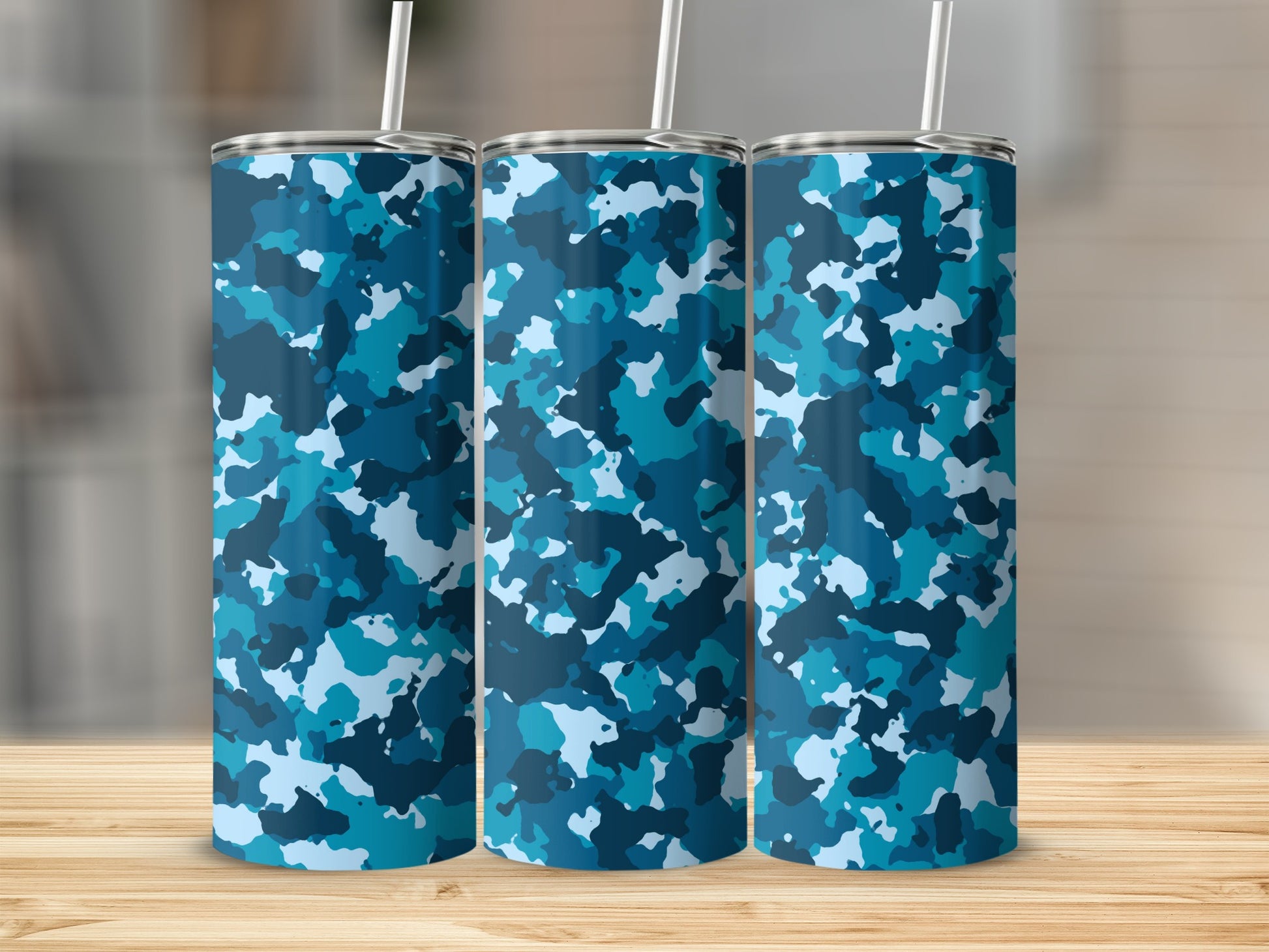 Three blue camouflage tumblers with straws arranged on a wooden surface.