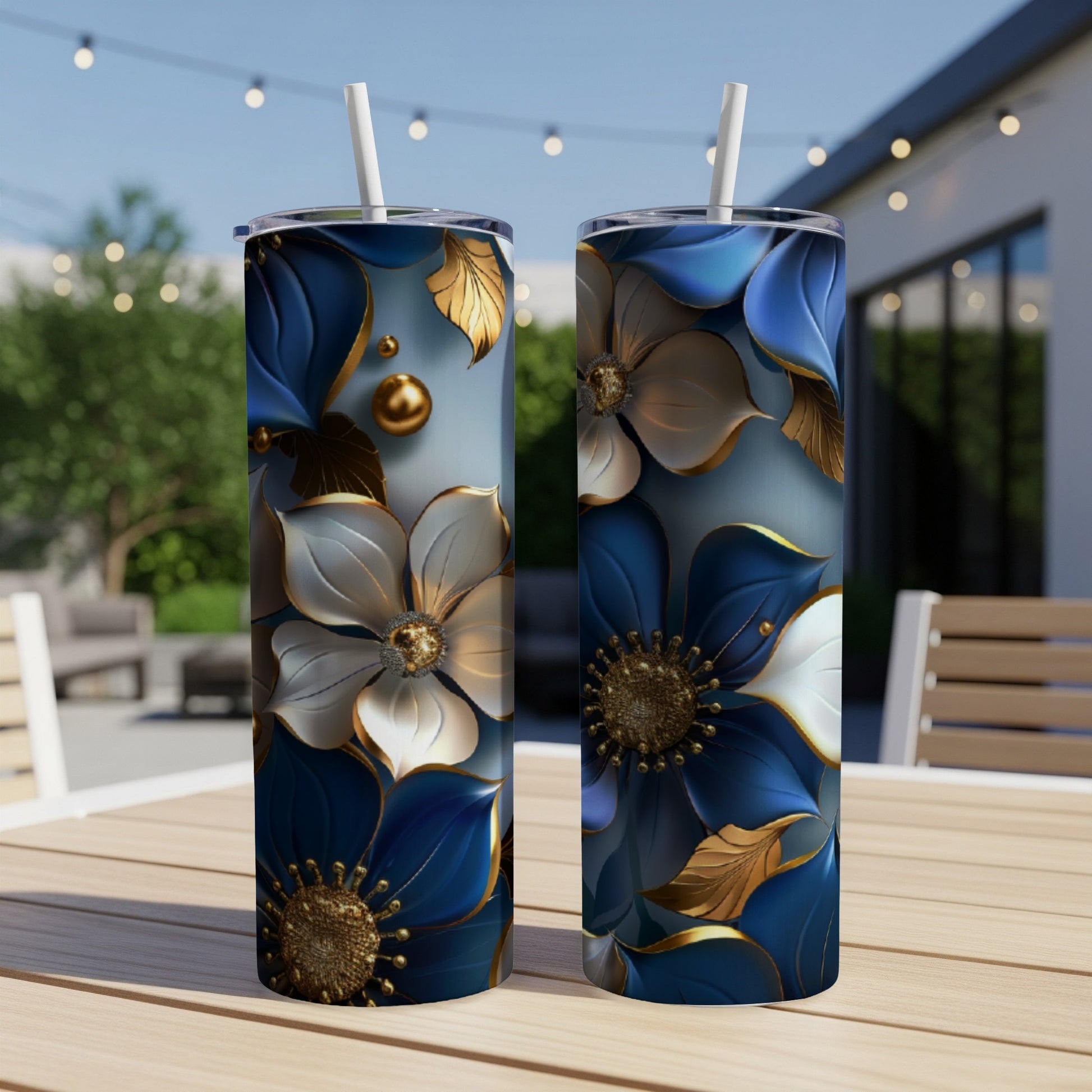 Two blue and gold floral tumblers with straws on a wooden table.
