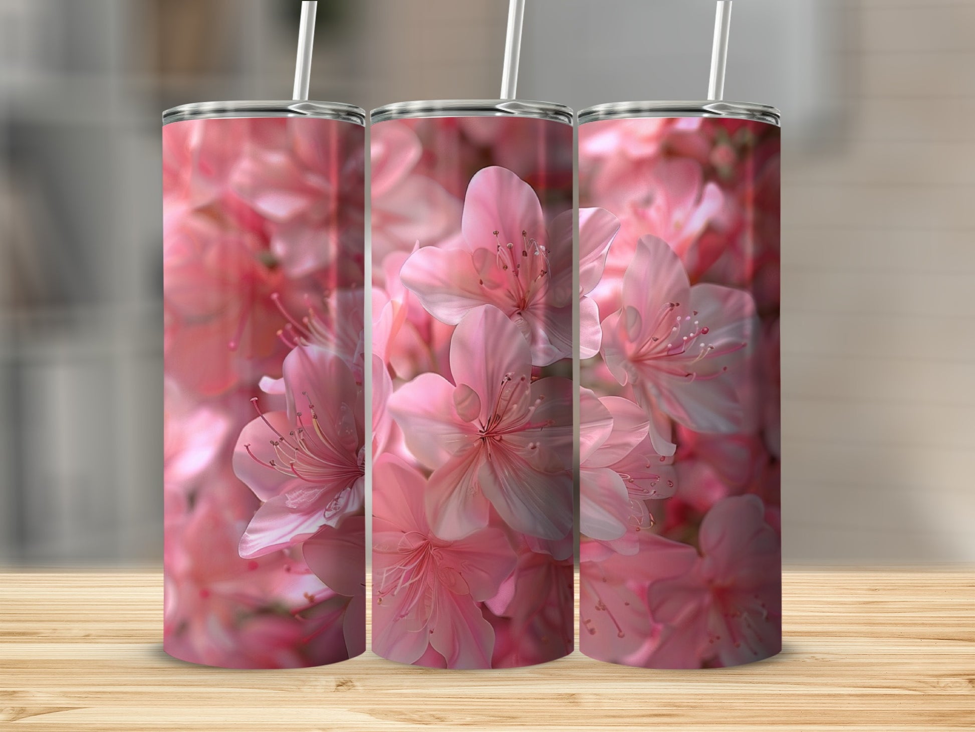 Three tumblers with a pink floral pattern displayed on a wooden surface.