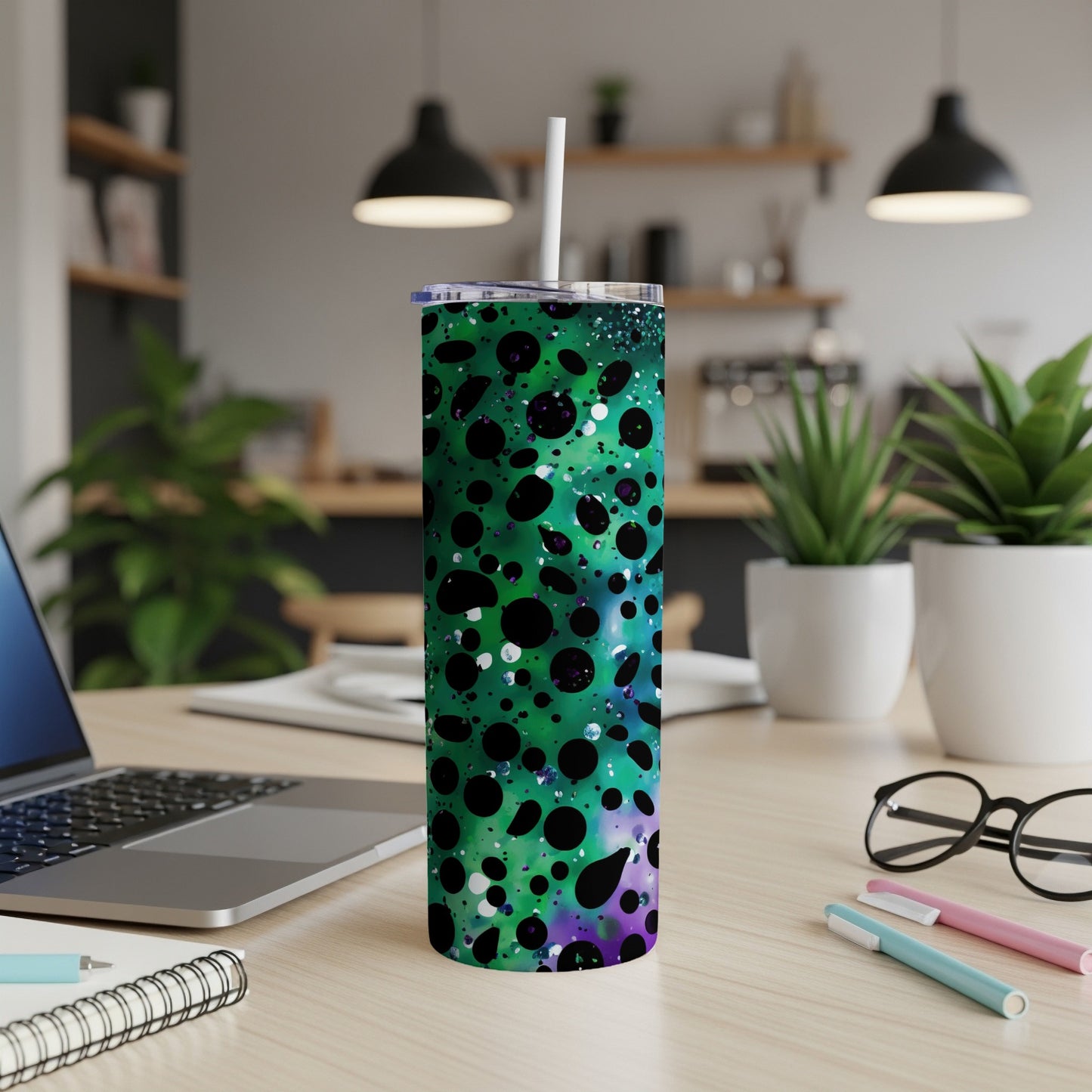 Green speckled tumbler with purple accents on a desk next to a laptop.