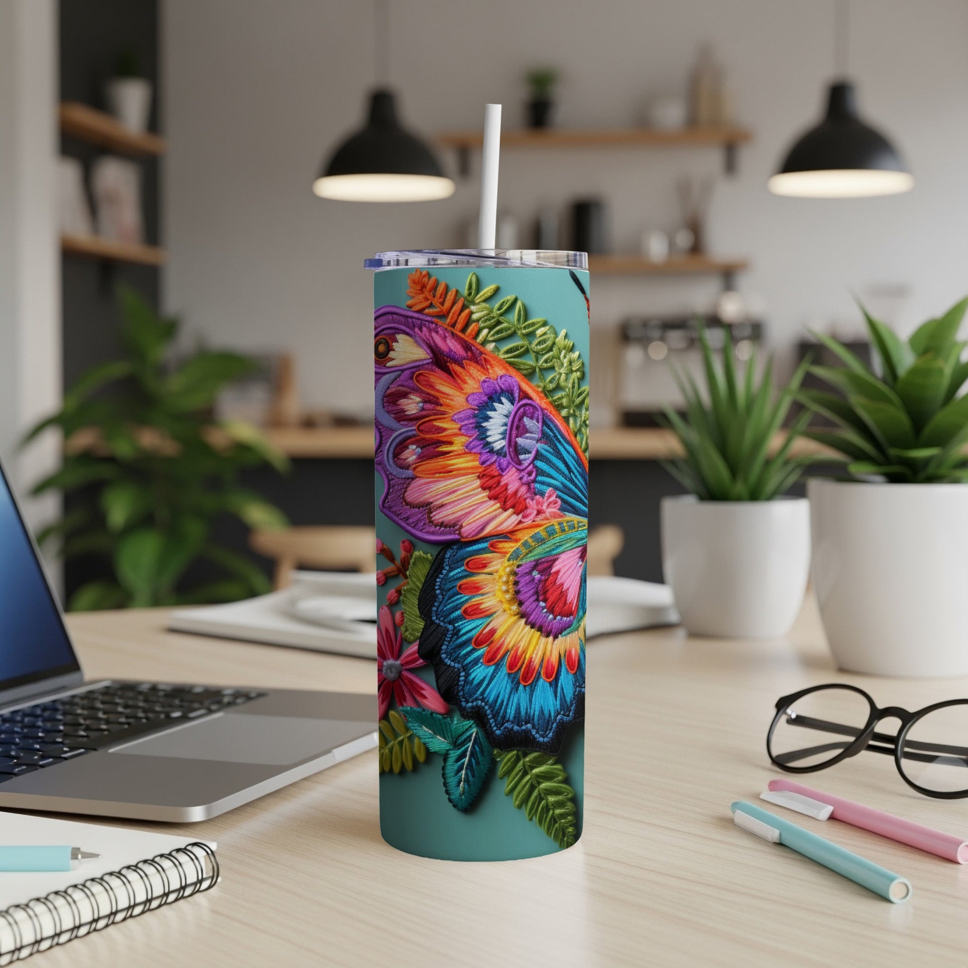 Detailed butterfly and floral design on a teal tumbler with a straw.