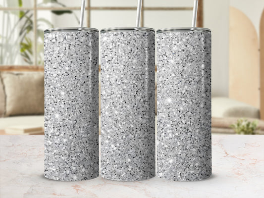 Three silver glitter tumblers with straws on a marble surface.
