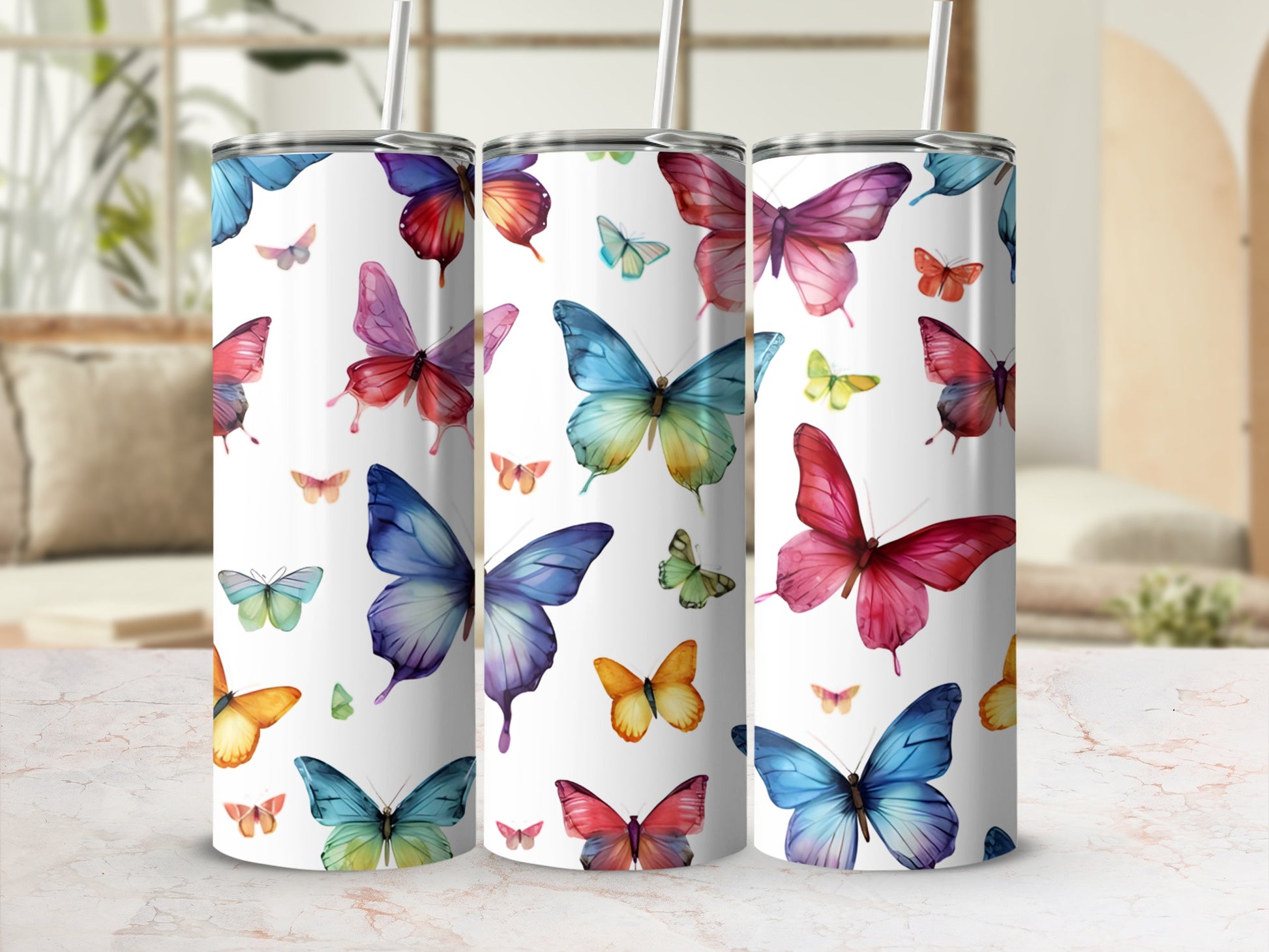 Three tumblers with colorful butterfly designs in a bright, airy setting.