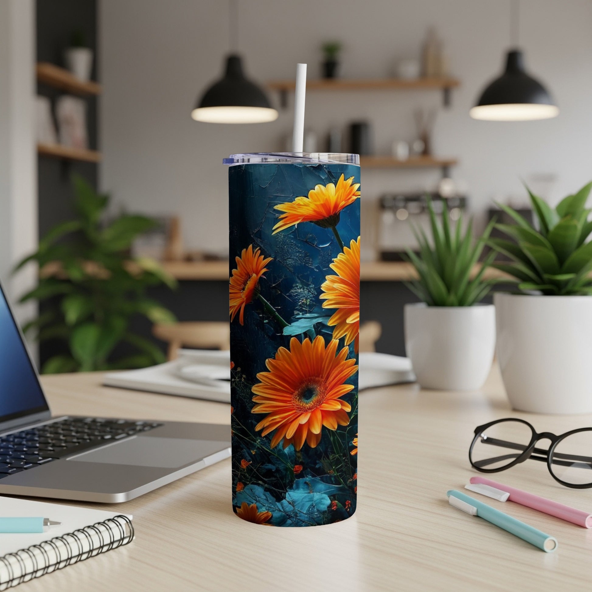 Tall tumbler with orange flowers and green leaves on a dark blue background.