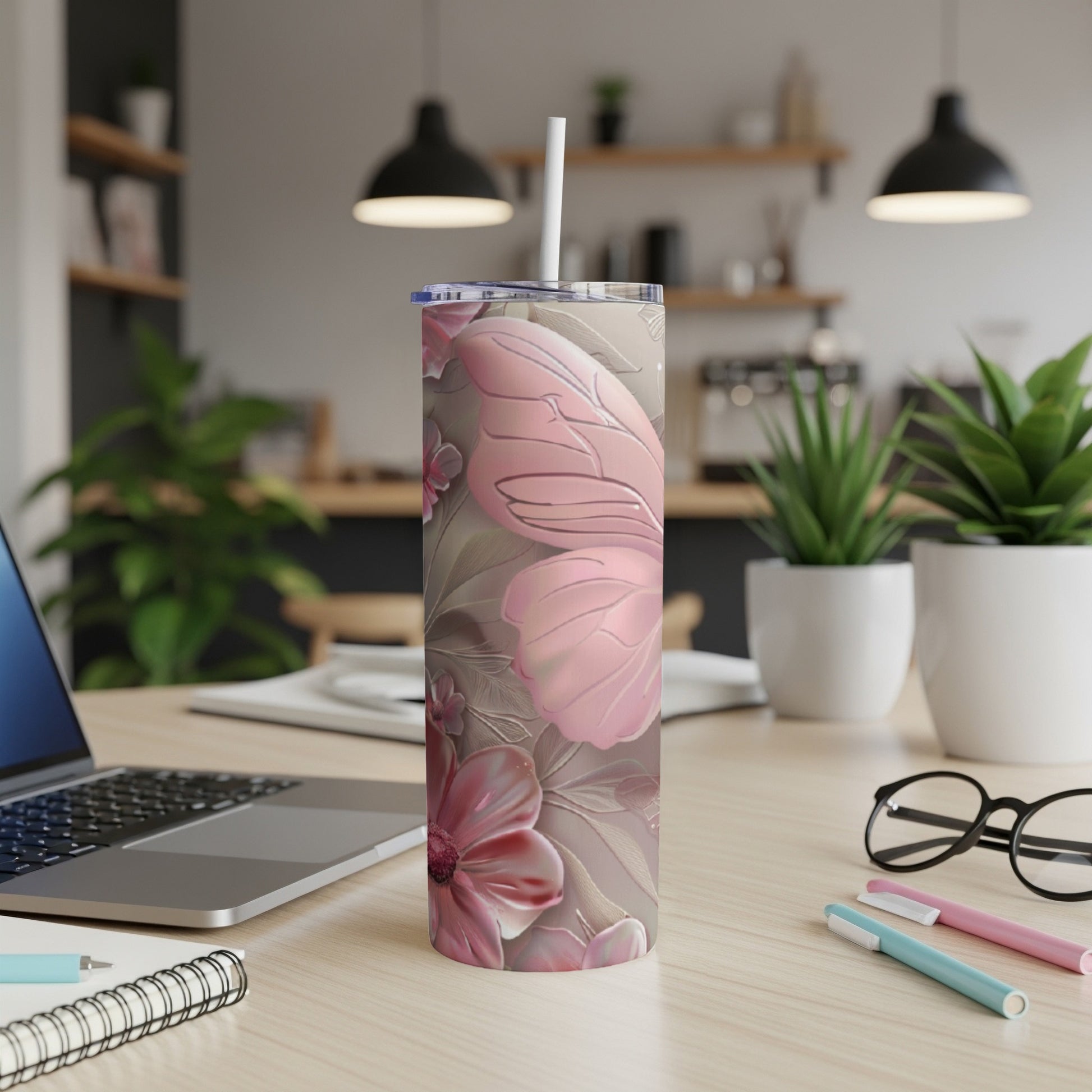 Floral patterned tumbler with butterfly design and straw on desk.