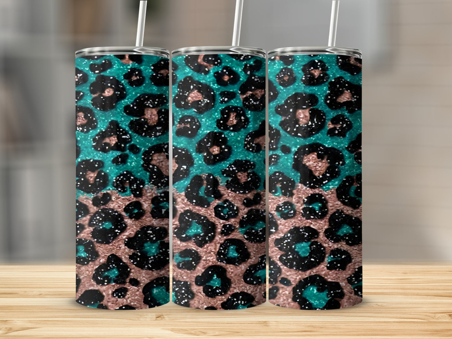 Three teal and black leopard print tumblers with straws on a wooden surface.