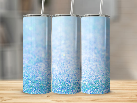 Three blue glitter tumblers with straws stand on a wooden surface.