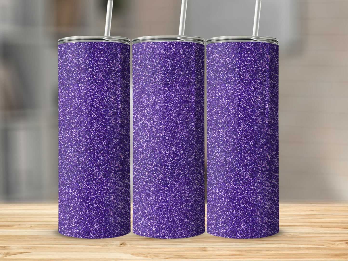 Three purple glitter stainless steel tumblers with straws on a wooden surface.