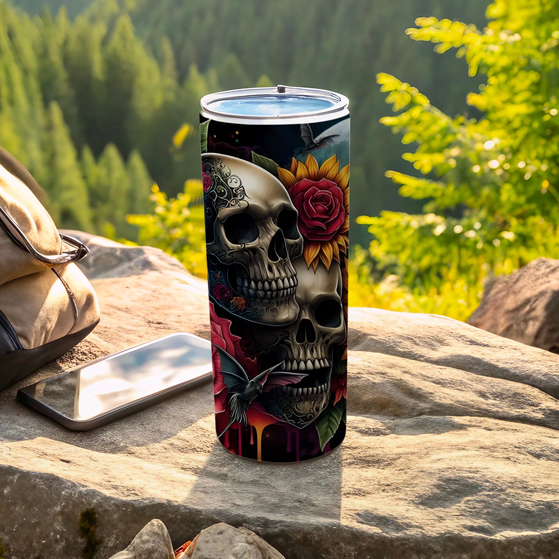 Two decorative skulls with floral accents on a black tumbler, outdoors.