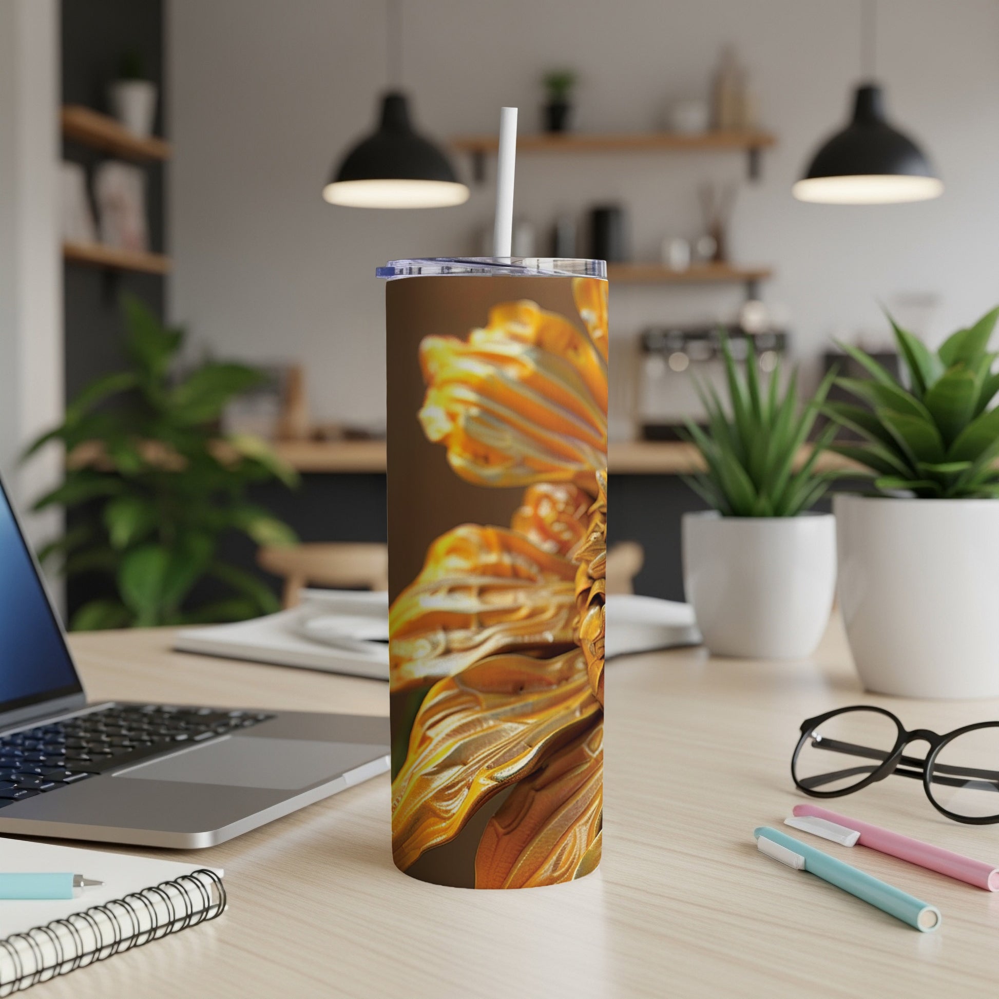 Tall tumbler with an abstract golden flower design on a desk.